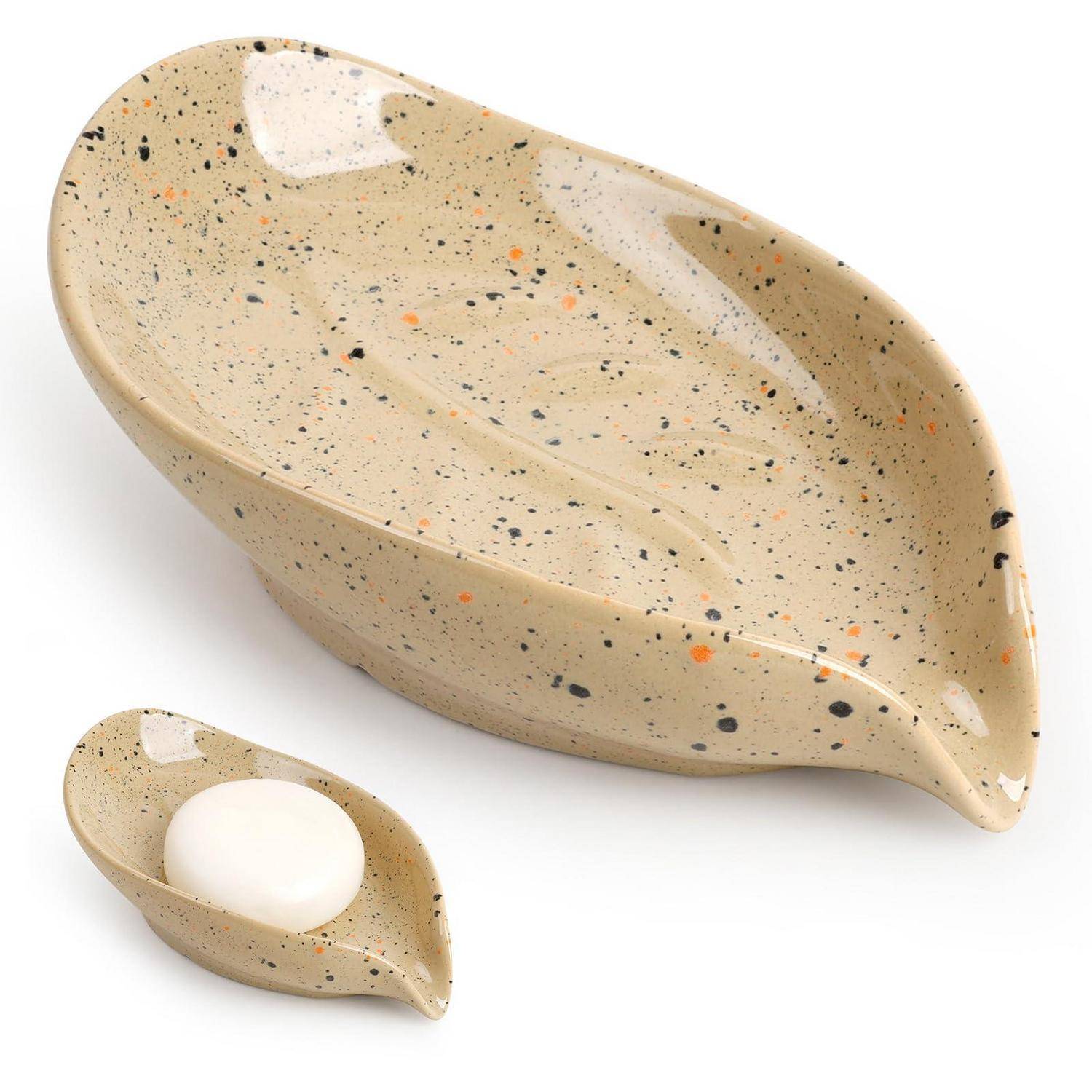 Gefleckte beige Keramikschüssel in Blattform, dargestellt mit einem passenden kleinen Löffelhalter, der ein weißes Ei hält.