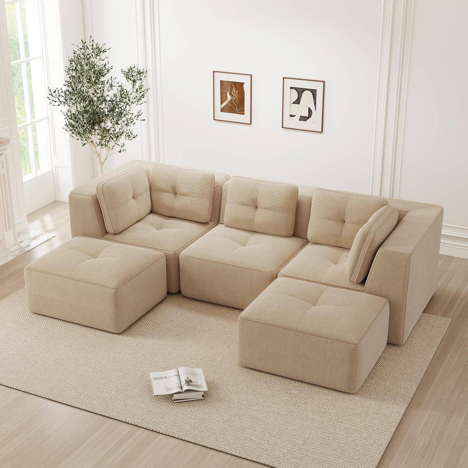 Beige modulares Ecksofa mit Ottomanen in einem hellen, minimalistischen Wohnzimmer, mit Wandkunst, einer Pflanze und einem aufgeschlagenen Buch auf dem Teppich.