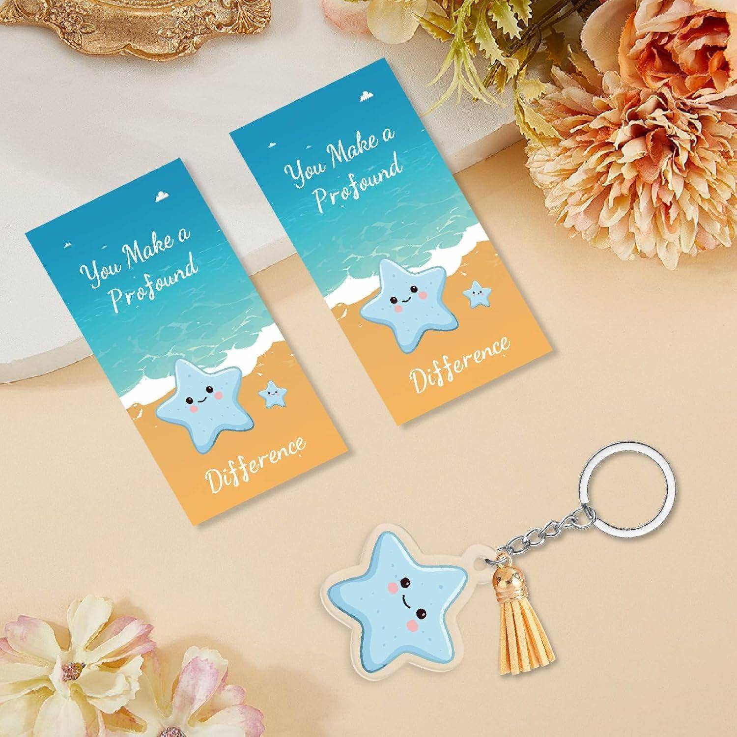 Zwei strandthematische Tags mit der Aufschrift „You Make a Profound Difference" mit einem lächelnden Stern-Schlüsselanhänger und einer Quaste auf beigefarbenem Hintergrund mit Blumen.