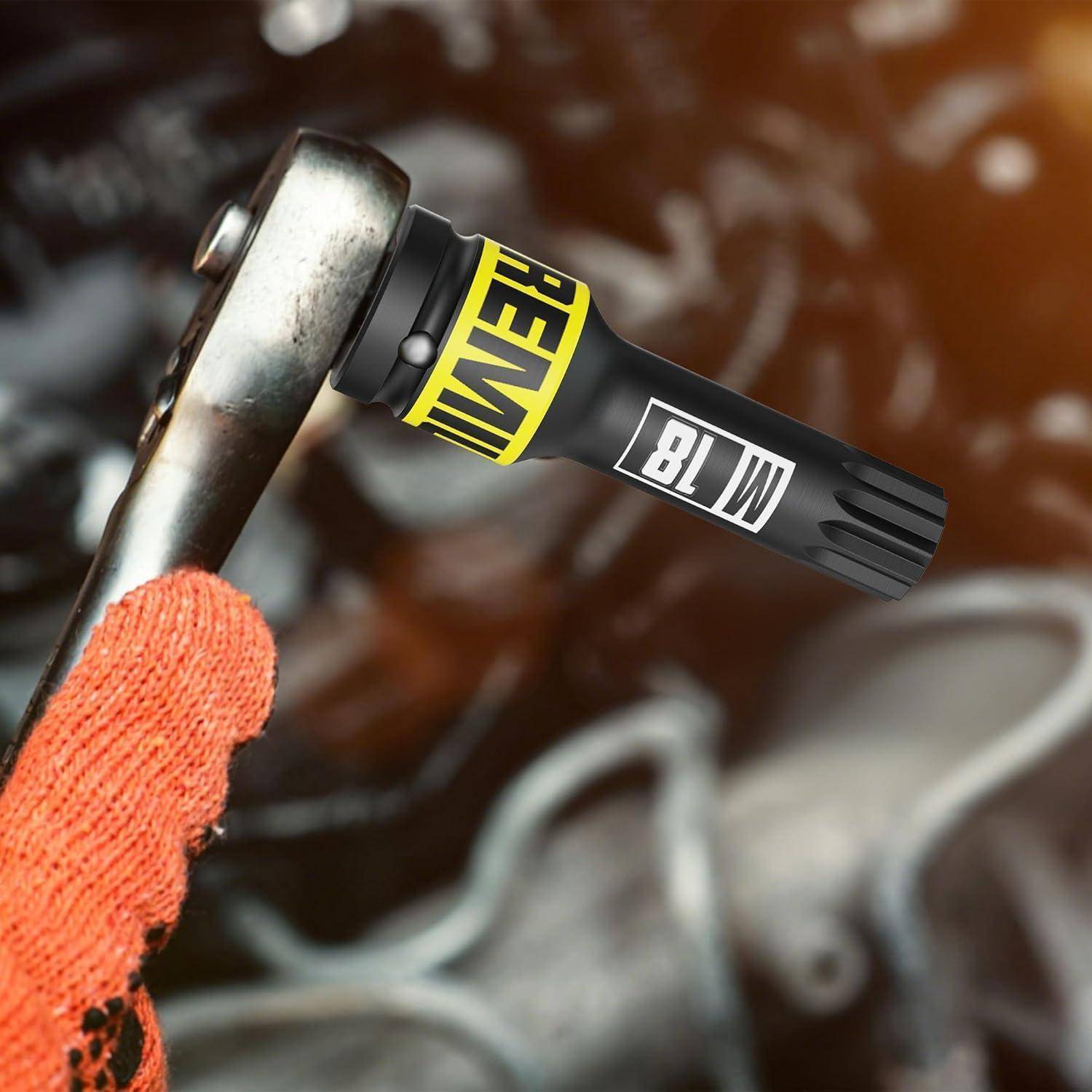 Behandschuhte Hand, die einen Schraubenschlüssel neben einem schwarzen M18-Batterie-Werkzeugadapter oder Aufsatz hält, mit sichtbaren Bezeichnungen 