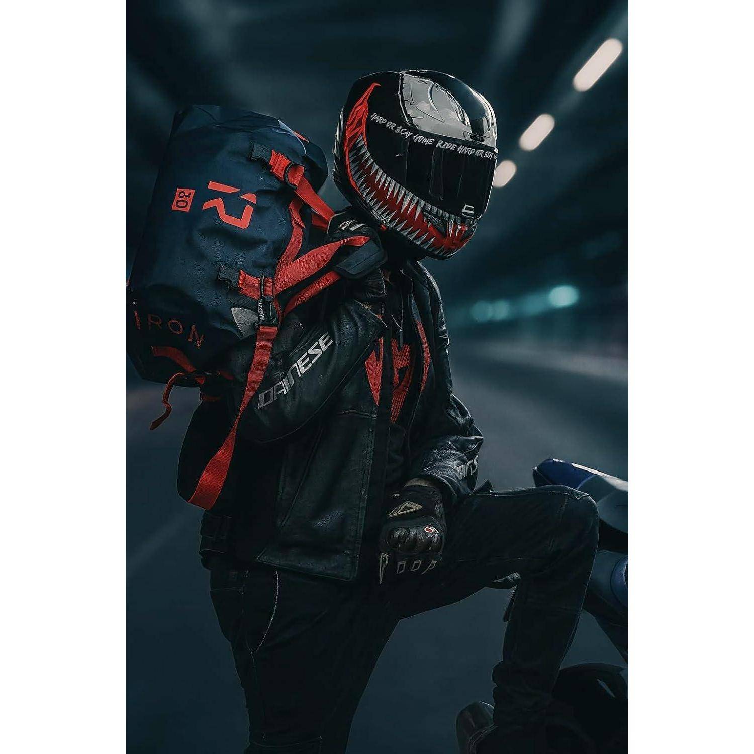 Motorradfahrer in schwarzer Ausrüstung und Helm steht mit einem großen Rucksack neben einem Motorrad in einem düsteren Tunnel und deutet auf eine Nachtfahrt oder einen Reisestopp hin.