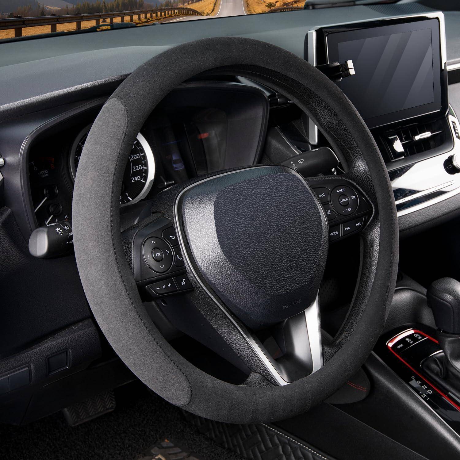 Nahaufnahme des Fahrzeuginnenraums mit einem Lenkrad mit schwarzem Wildlederbezug und Armaturenbrettreglern, einschließlich eines zentralen Touchscreens.