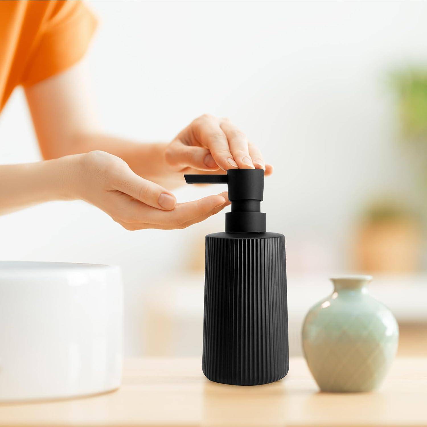 Hände drücken auf einen schwarzen Pumpspender und deuten darauf hin, dass Seife oder Lotion auf einer Badezimmerablage ausgegossen wird, mit einer Vase in der Nähe.