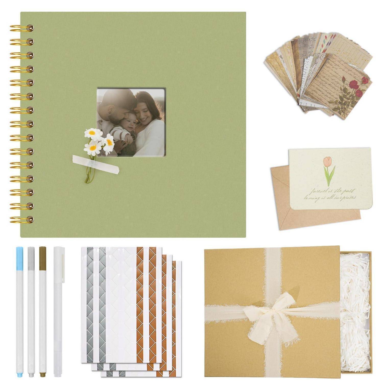 Scrapbooking-Set mit einem grünen spiralgebundenem Fotoalbum, Dekorpapieren, Stiften, einer Geschenkbox und Blumenkarten auf weißem Hintergrund.