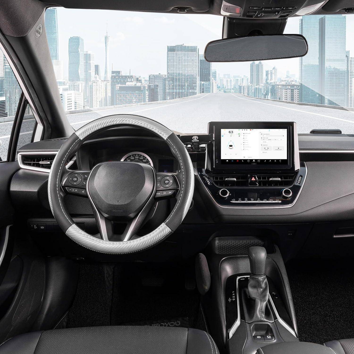 Innenraum eines modernen Autos, der das Lenkrad, den Touchscreen-Armaturenbrett und den Schaltknüppel mit einer Stadtsilhouette zeigt, die durch die Windschutzscheibe sichtbar ist.