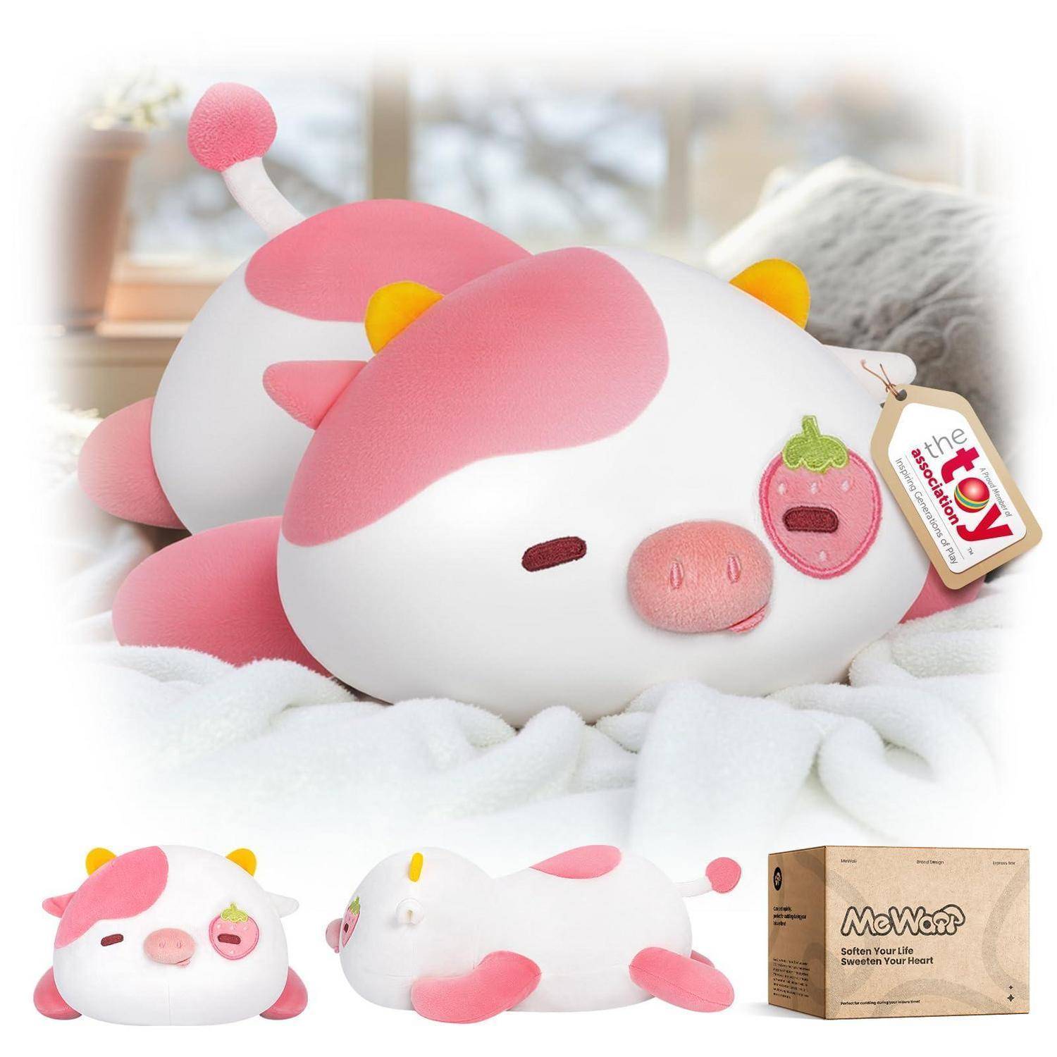 Kuscheliges rosa-weißes Kuhspielzeug in Schlafposition, gezeigt auf einem Bett und in drei Produktansichten mit einem „the cow