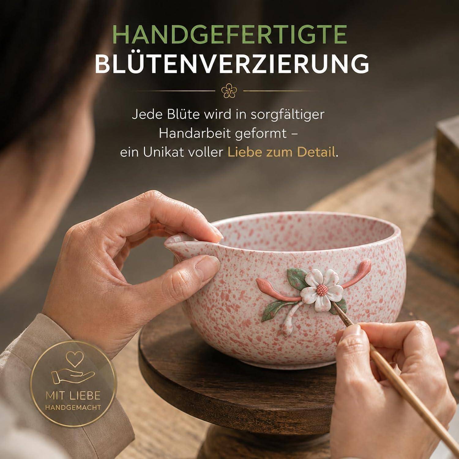 Hände, die eine Keramikschale mit einer kleinen Blume verzieren; der Text besagt „Handgefertigte Blütenverzierung" und vermerkt, dass jede Blume sorgfältig von Hand gefertigt wird.