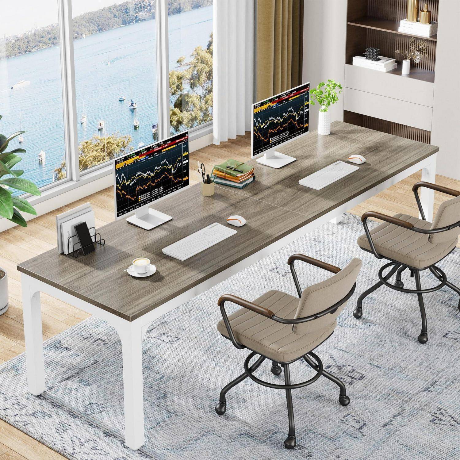Modernes Home Office mit zwei Desktop-Monitoren, auf denen Börsendiagramme angezeigt werden, auf einem großen Schreibtisch neben einem Fenster mit Blick auf das Wasser.