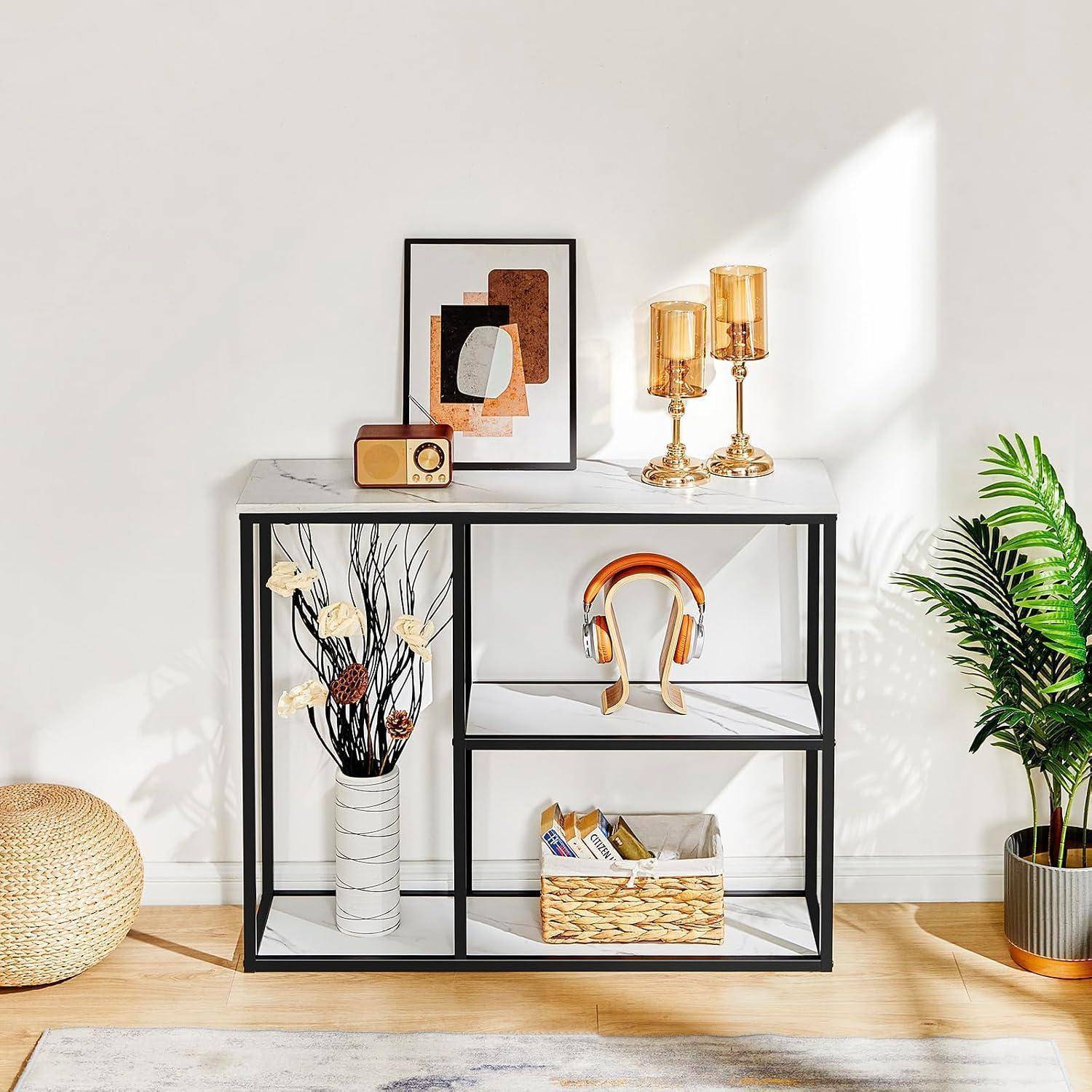 Stilvoller Konsolentisch mit gerahmter Kunst, goldenen Kerzenständern, vintage Radio, Kopfhörern, Blumen und Korb in einem hellen minimalistischen Raum.