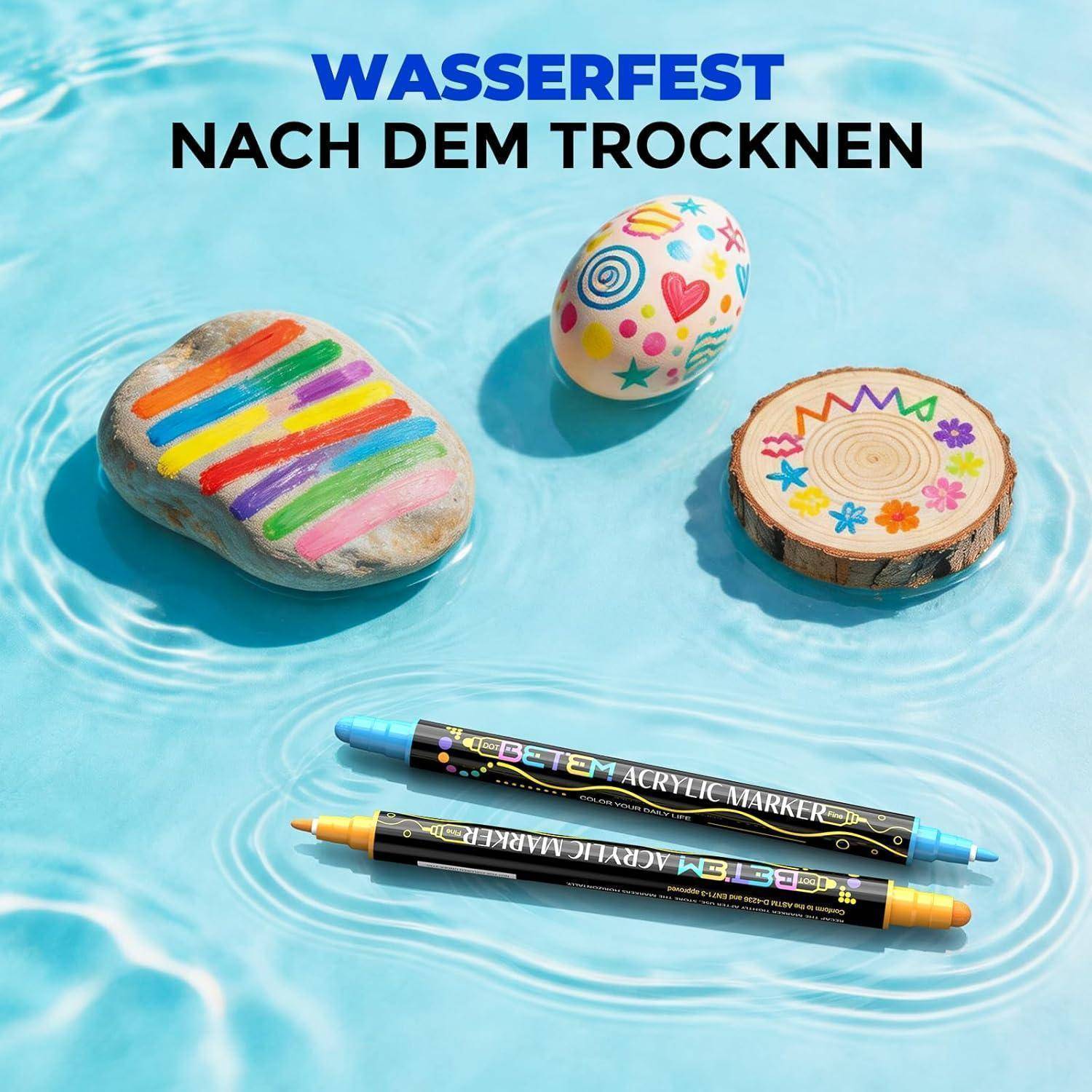 Drei bemalte Steine und zwei Acrylfarben-Marker auf blauem Wasserhintergrund mit deutschem Text „WASSERFEST NACH DEM TROCKNEN" darüber.