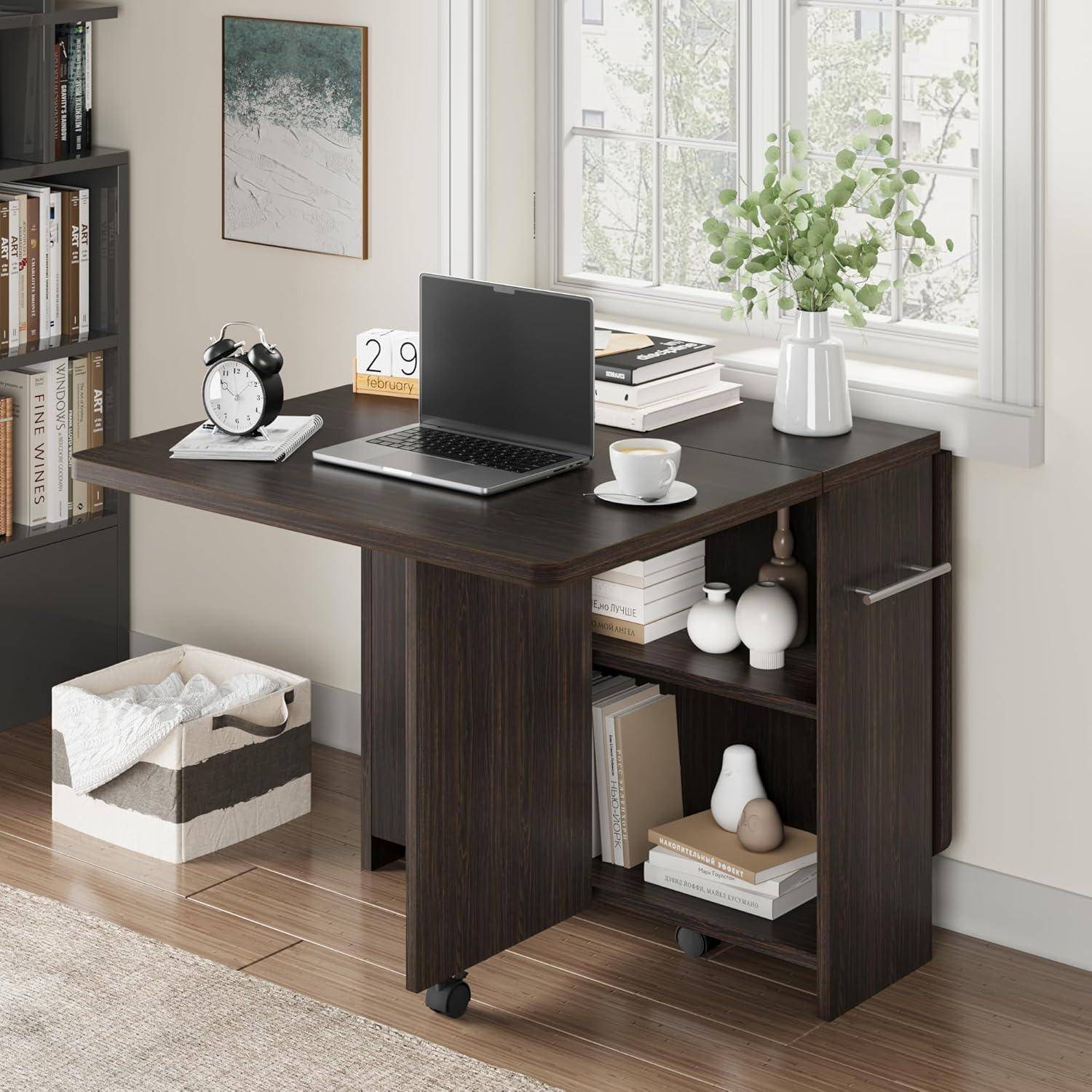 Kompakter dunkler Holz-Schreibtisch für das Homeoffice mit aufgeklapptem Laptop, Wecker, Kalender, Kaffeetasse, Büchern und Vase neben einem hellen Fenster