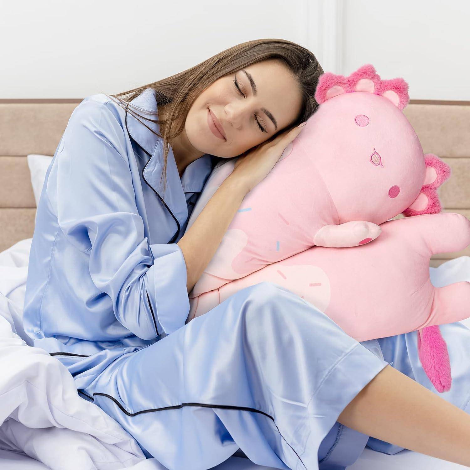 Eine Frau in blauen Pyjamas schläft im Bett, während sie ein großes rosa Plüschtier umarmt.