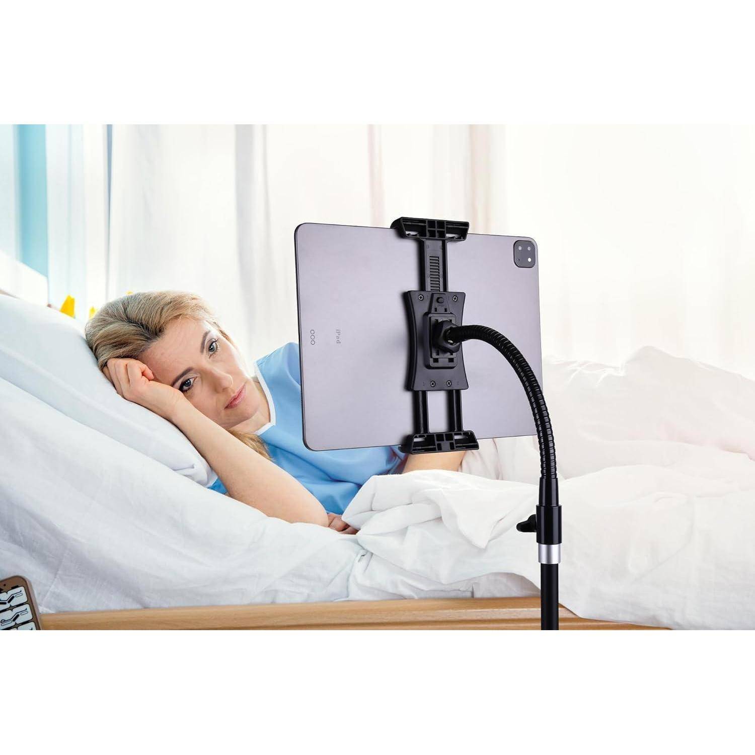 Eine Frau liegt im Bett und schaut auf ein Tablet, das auf einem flexiblen Ständer montiert ist, was freihändiges Anschauen im Schlafzimmer ermöglicht.