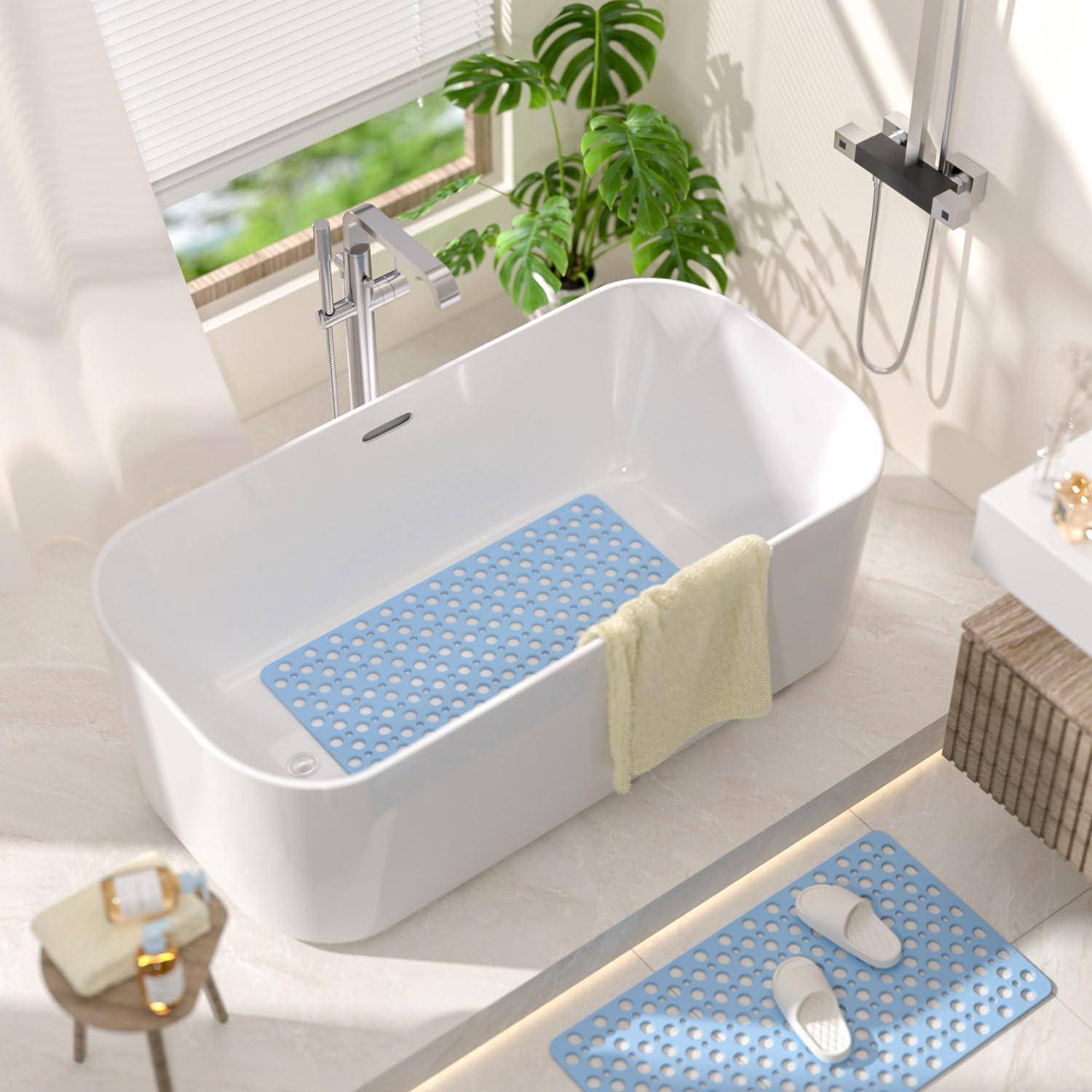 Modernes Badezimmer mit einer freistehenden weißen Badewanne und separater Badmatte auf dem Boden; ein Handtuch hängt an der Wanne, mit Fenster, Pflanze und Duschvorrichtungen in der Nähe.