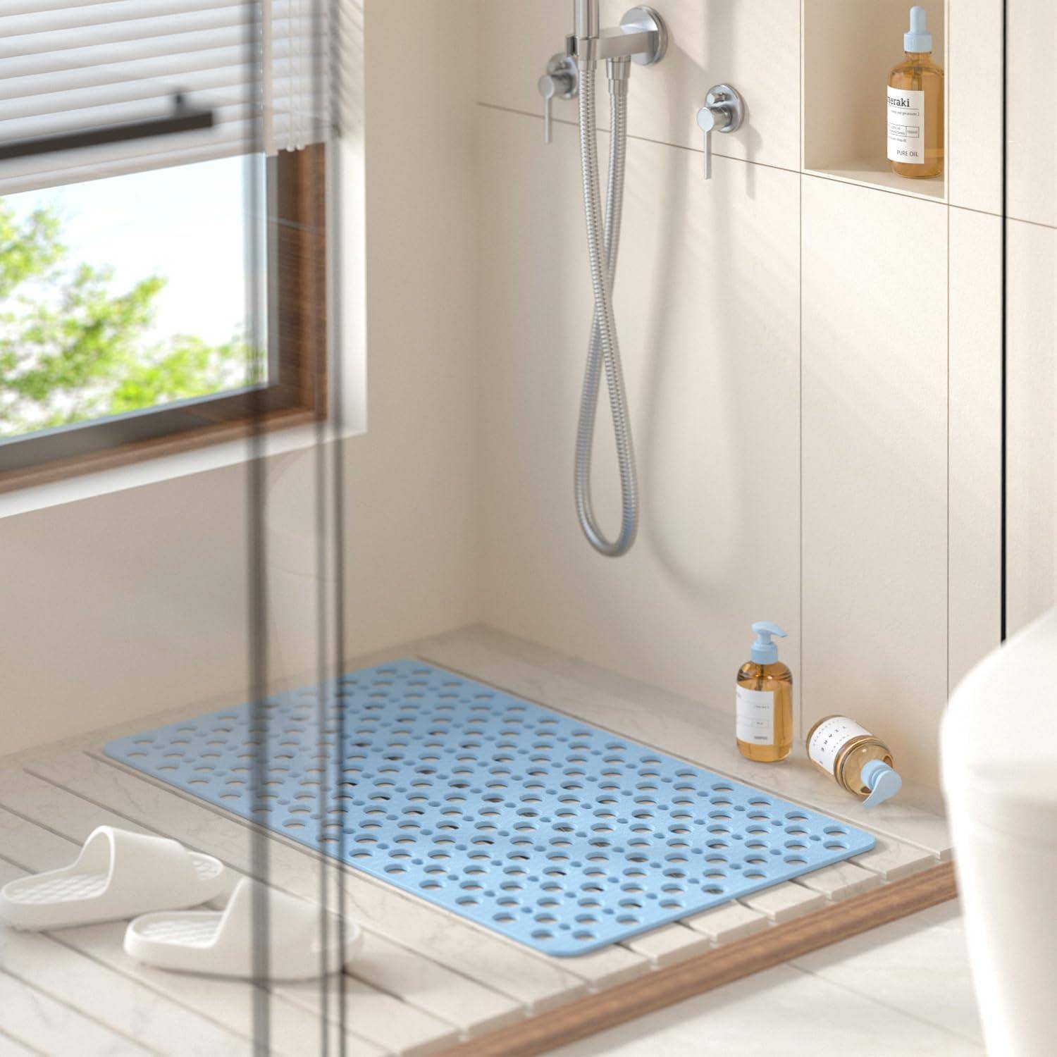 Modernes Badezimmer mit einer wandmontierten Handbrause, blauer rutschfester Matte, Badepantoffeln und zwei bernsteinfarbenen Pumpflaschen auf einer gefliesten Bank und einem Regal.