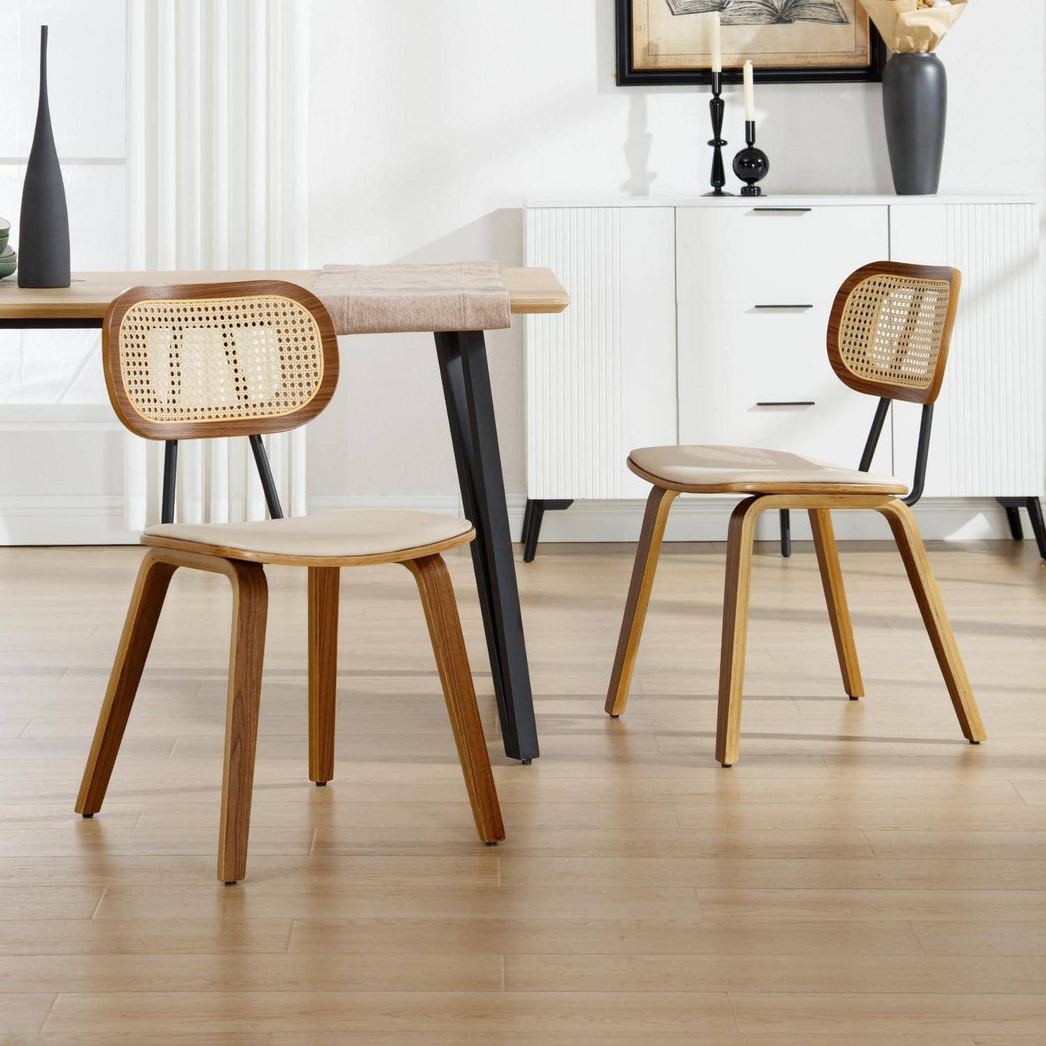 Zwei Holzesszimmer-stühle mit geflochtenen Rohrücken und -sitzen in einem modernen Esszimmer, dargestellt neben einem Tisch und einem weißen Sideboard.