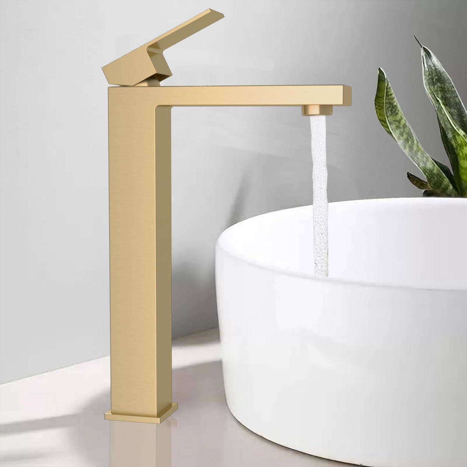 Moderner goldfarbener Badezimmerwasserhahn, der Wasser in ein weißes Waschbecken gießt, mit einer Pflanze im Hintergrund.