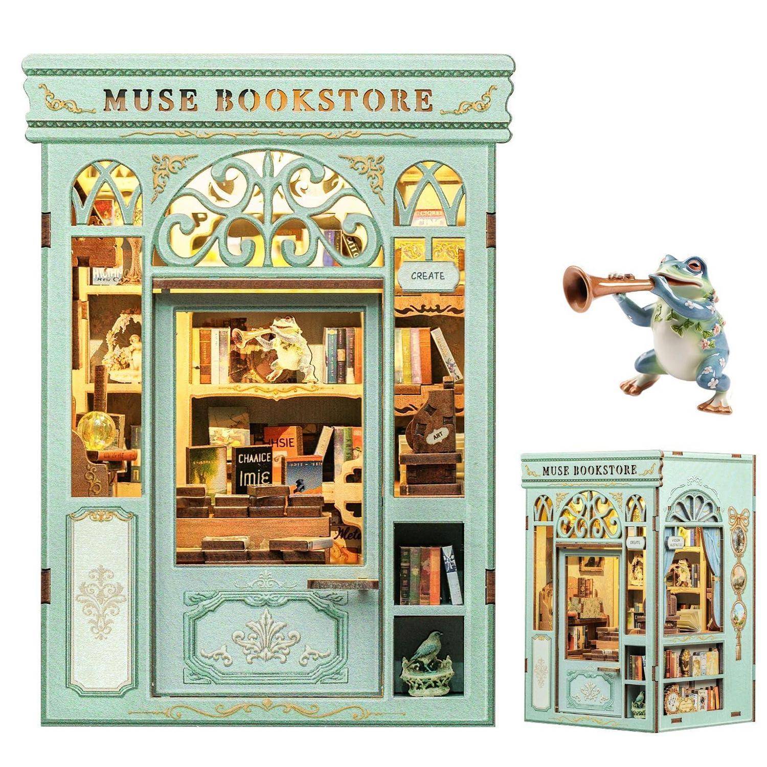 Dekorative Miniatur-'MUSE BOOKSTORE'-Ausstellung mit blaugrüner Ladenfassade, beleuchteten Regalen und einem kleinen Frosch, der daneben Trompete spielt.