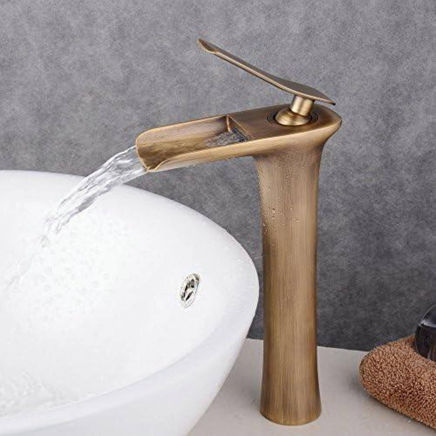 Bronzefarbener Wasserfallstil-Badezimmerhahn, der Wasser in ein weißes Aufsatzwaschbecken gießt.