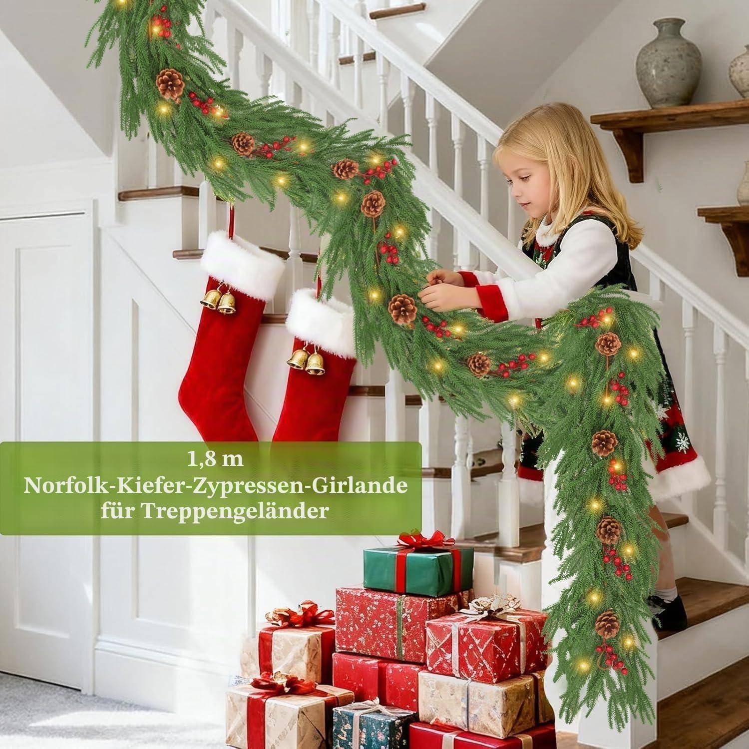 Mädchen, das eine Treppengeländergirlande mit Lichtern, Tannenzapfen und roten Beeren dekoriert; Weihnachtssocken und verpackte Geschenke in der Nähe. Text liest sich wie folgt: „1,8 m Norfolk-Kiefer-Zypressen-Girlande für Treppengeländer".