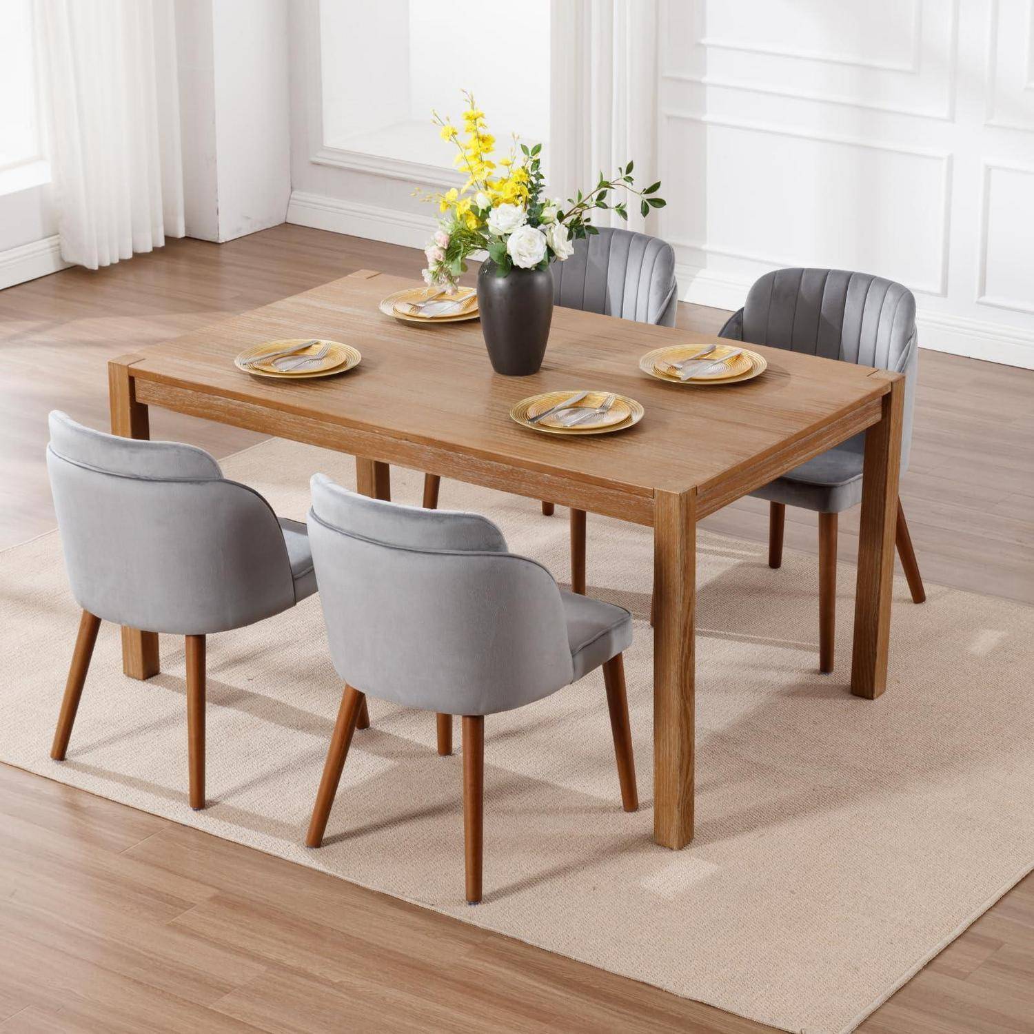 Holzesszimmertischset für vier Personen mit grau gepolsterten Stühlen und einer Blumenvase auf einem hellen Teppich in einem hellen Raum.
