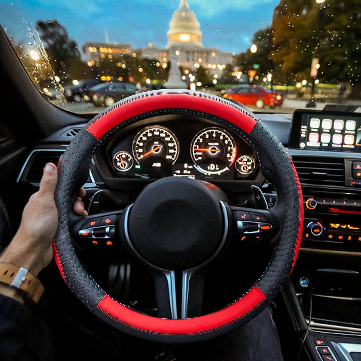 Fahrerblick im Inneren eines Autos mit einem rot-schwarzen Lenkrad, beleuchtetem Armaturenbrett und Stadtgebäude, das bei Dämmerung durch die Windschutzscheibe sichtbar ist.