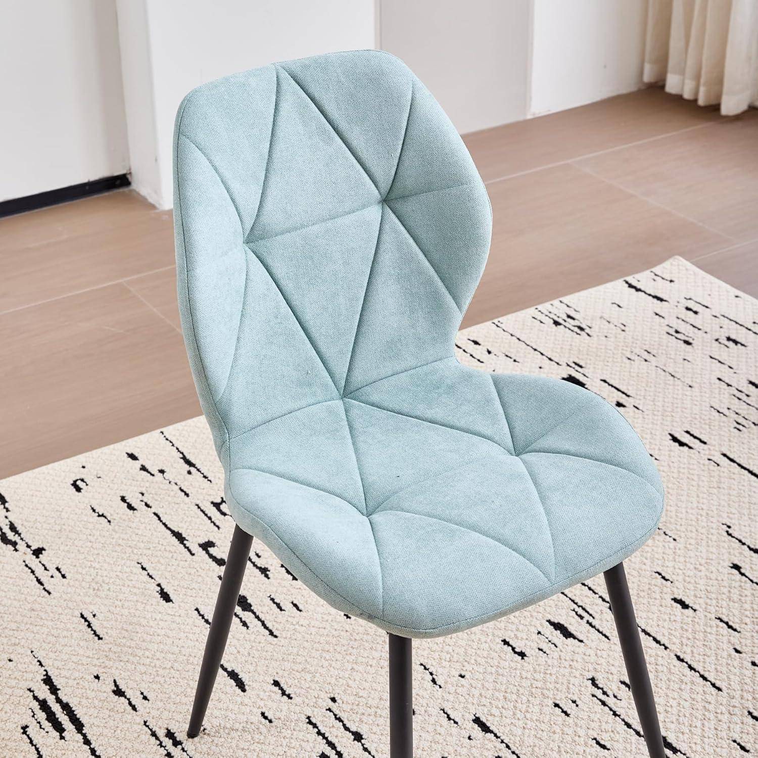 Hellblauer gepolsterter Akzentualstuhl mit schwarzen Beinen auf einem gemusterten Teppich in einem minimalistischen Raum.