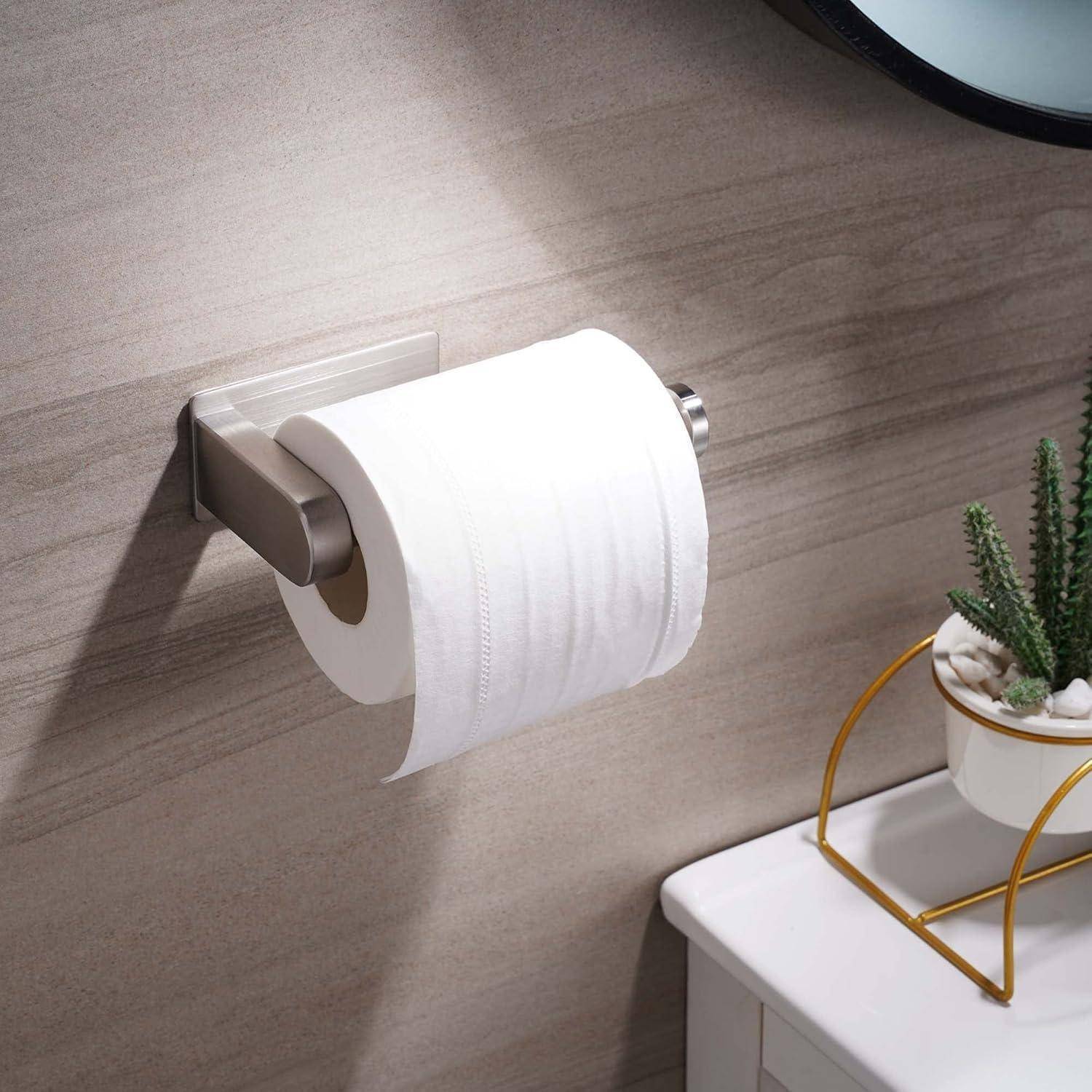 Wandmontierter Toilettenpapierhalter mit einer Rolle weißem Toilettenpapier neben einer Topfpflanze auf der Arbeitsplatte und einem dekorativen Metallständer.