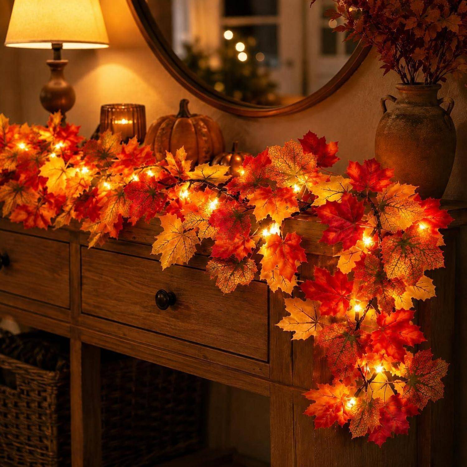 Holzkonsole, dekoriert mit leuchtender Herbstlaubgirlande, Kürbissen und einer Lampe in einem gemütlichen Zimmer.