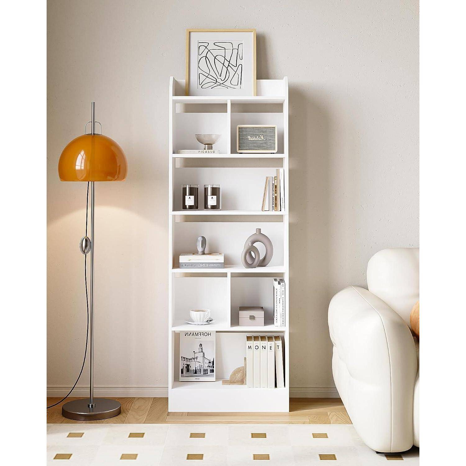 Moderne Wohnzimmerecke mit weißem Bücherregal-Dekor und einer orangefarbenen Stehleuchte neben einem weißen Sessel.
