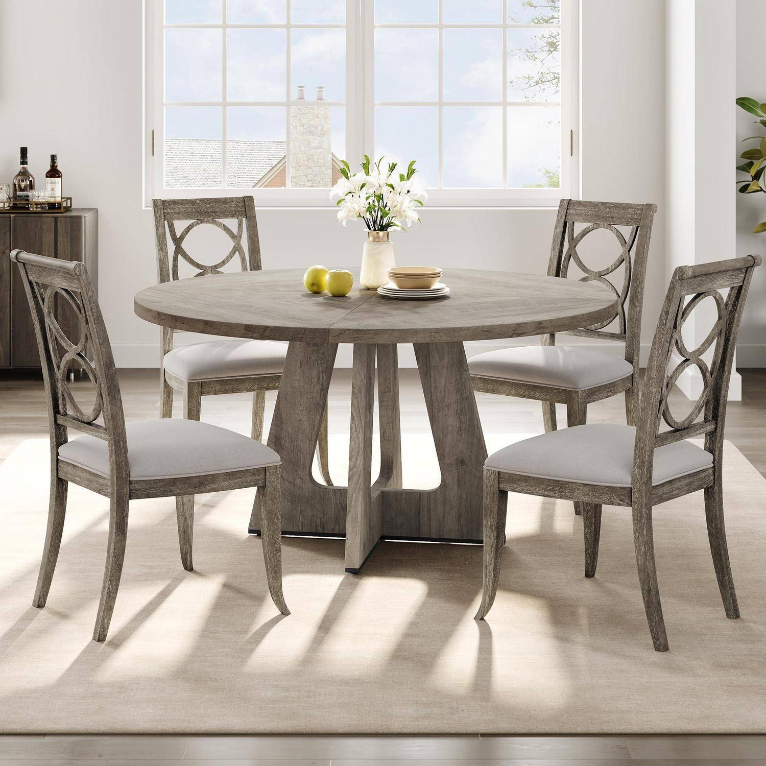 Runder Holzesstisch mit vier gepolsterten Stühlen in einem hellen Raum, mit einer Blumenvase und Tischbesteck darauf.