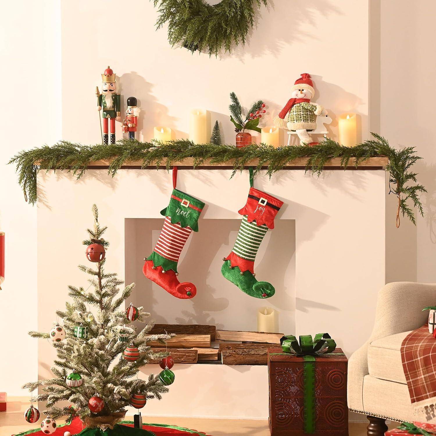 Verzierter Weihnachtskamin mit Strümpfen, Kerzen, Nussknacker und kleinem Baum neben einem verpackten Geschenk in einem gemütlichen Wohnzimmer.