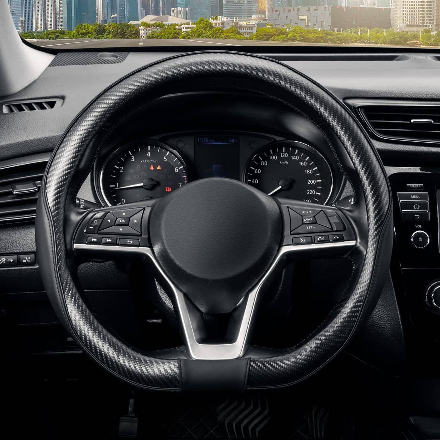 Blick auf das Autoinnenraum von der Fahrerposition aus, der ein schwarzes Lenkrad mit Instrumententafel und Mittelbedienfeldern zeigt, durch die Windschutzscheibe ist eine Stadtsilhouette zu sehen.