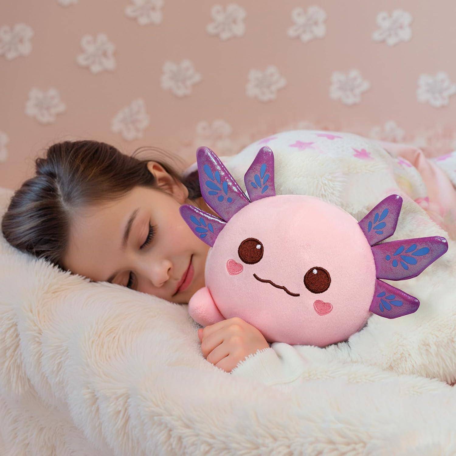 Ein schlafendes Kind kuschelt sich an ein rosa weiches Plüsch-Axolotl-Spielzeug in einem weichen weißen Bett und schafft eine gemütliche, friedliche Szene.