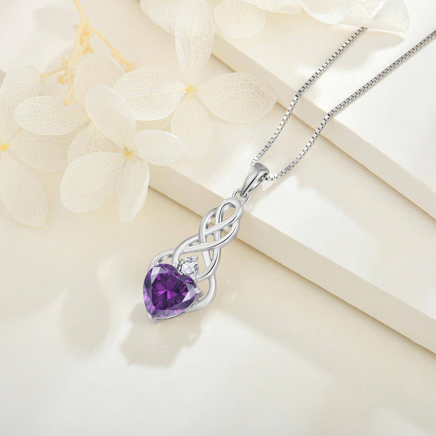 Silberne Halskette mit einem verflochtenen Anhänger, der einen violetten herzförmigen Edelstein hält, auf hellem cremefarbenem Hintergrund mit Blumendekoration dargestellt.
