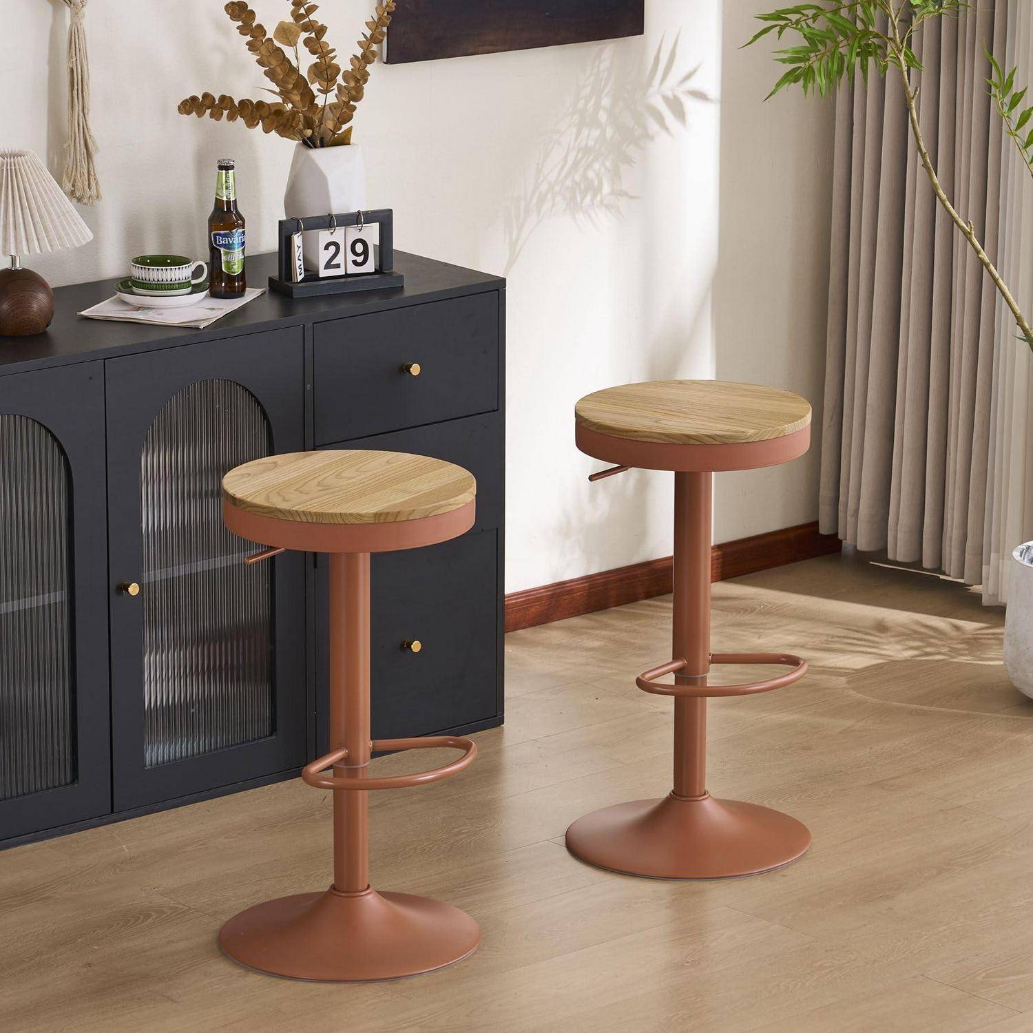 Zwei moderne verstellbare Barhocker mit runden Holzsitzen und kupfernen Untergestellen in einem hellen Wohnzimmer neben einem schwarzen Schrank.