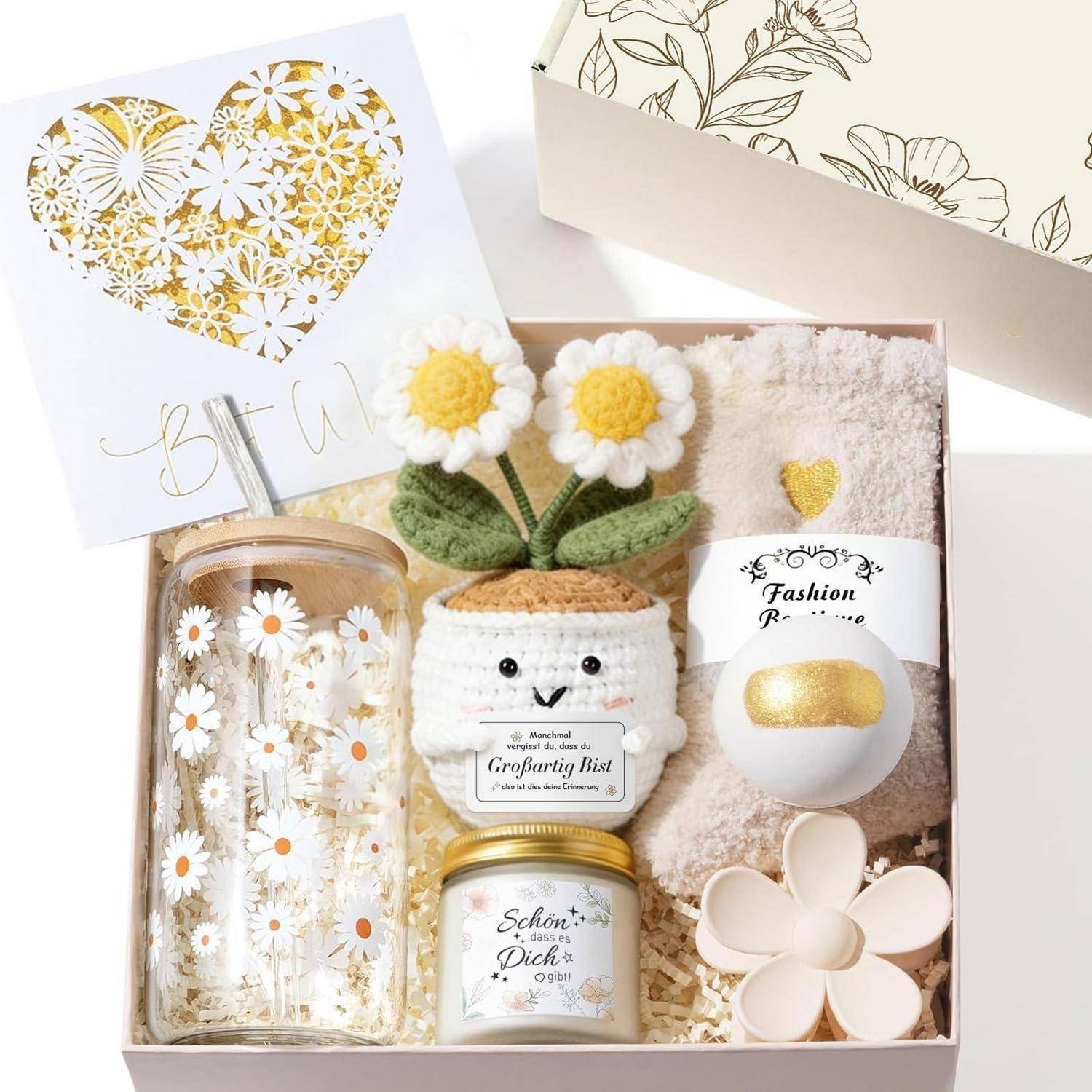 Geschenkbox mit gänseblümchenthematischem Trinkbecher, gehäkelter Pflanze, Kerze im Glas, Handtuch, Badebombe und Blumenclip, arrangiert als fröhliches Geschenkset.