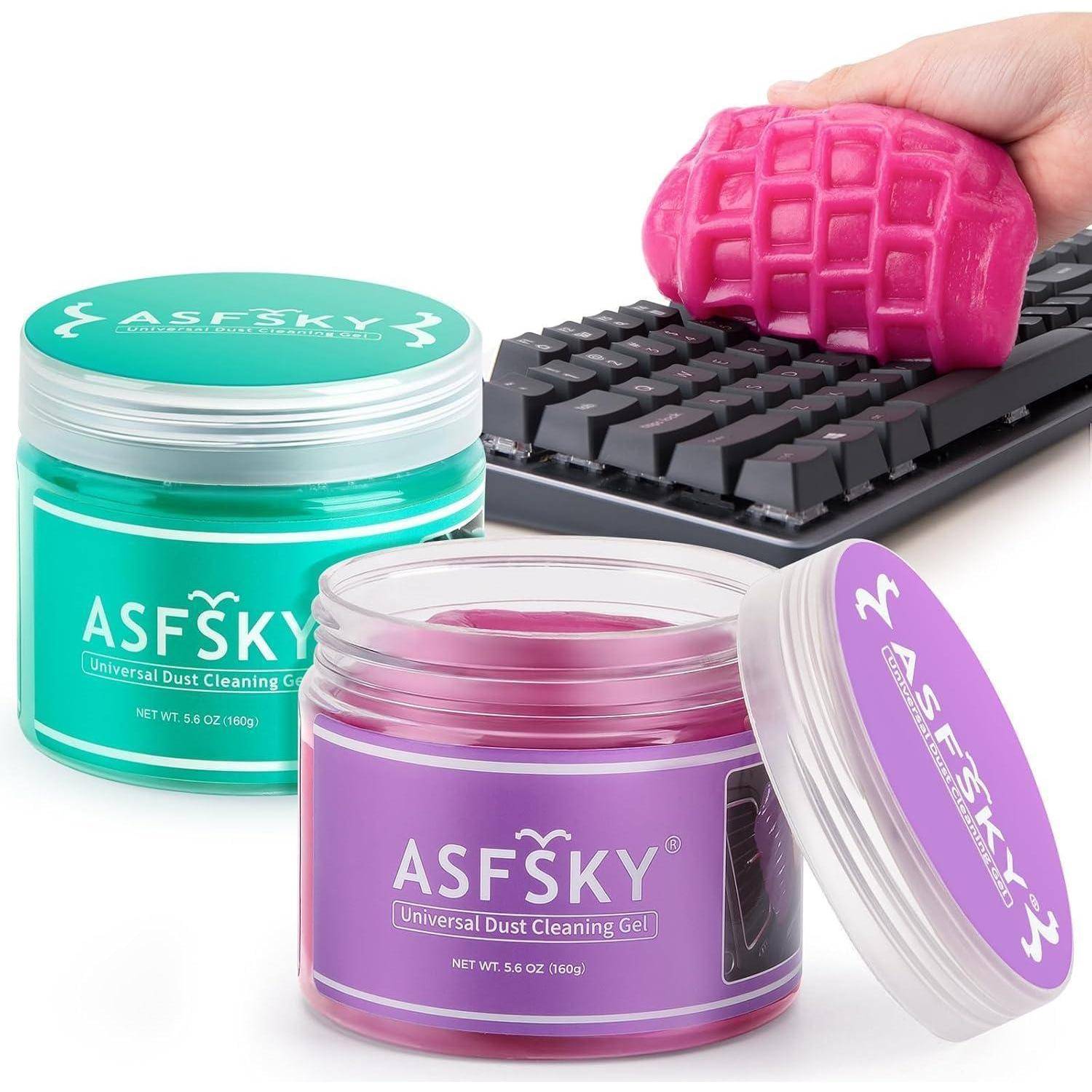 Drei Gläser ASFSKY Universal-Staubentfernungsgel in Blaugrün, Lila und Rosa, mit einer Hand, die rosafarbenes Gel in eine Tastatur drückt, um Staub zu entfernen.