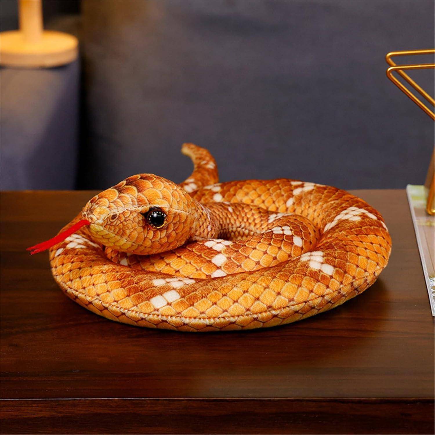 Aufgerollte orange-weiße Schlangenfigur auf einem Holztisch, mit roter Zunge und aufgerichttem Schwanz.