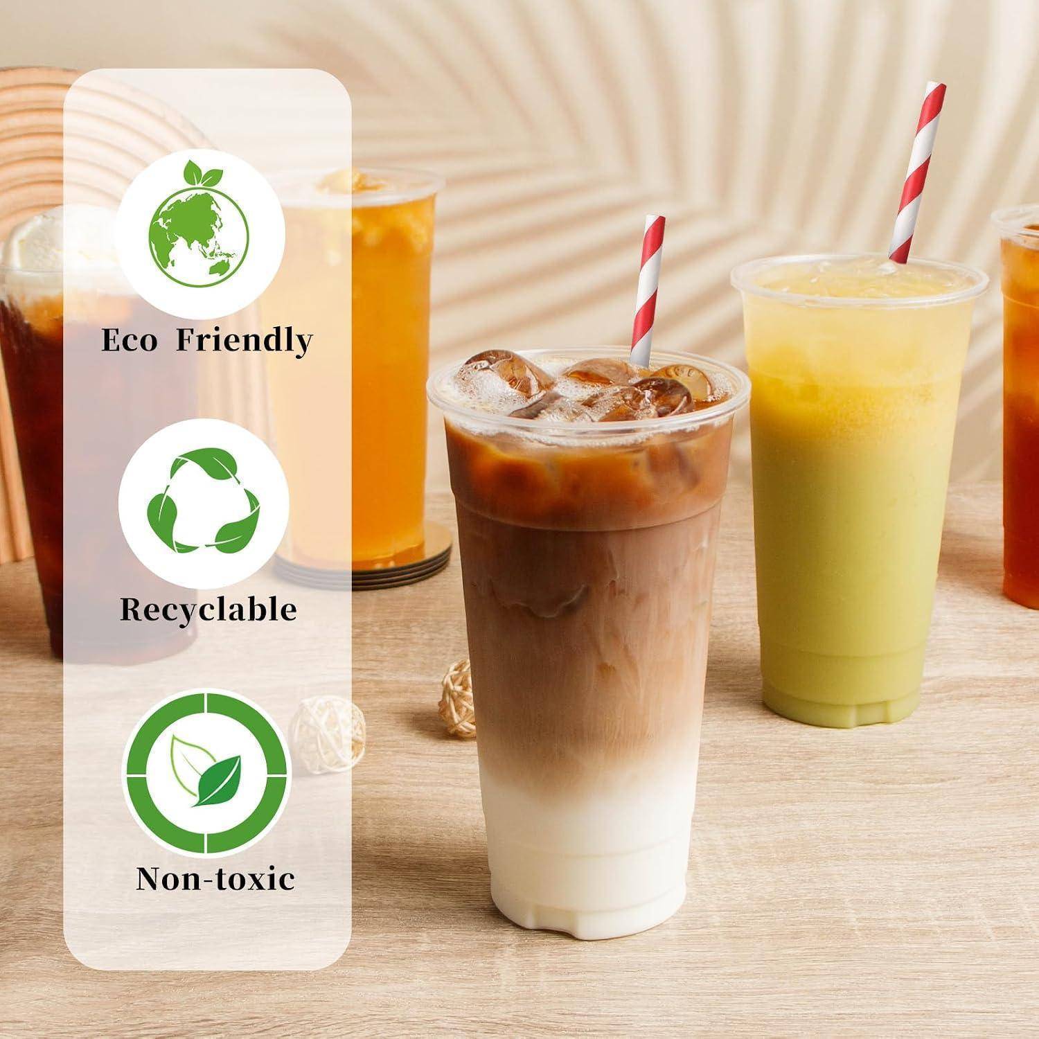 Umweltfreundliche, recycelbare, ungiftige Tassen mit eisgekühlten Getränken und gestreiften Strohhalmen auf einem Tisch.