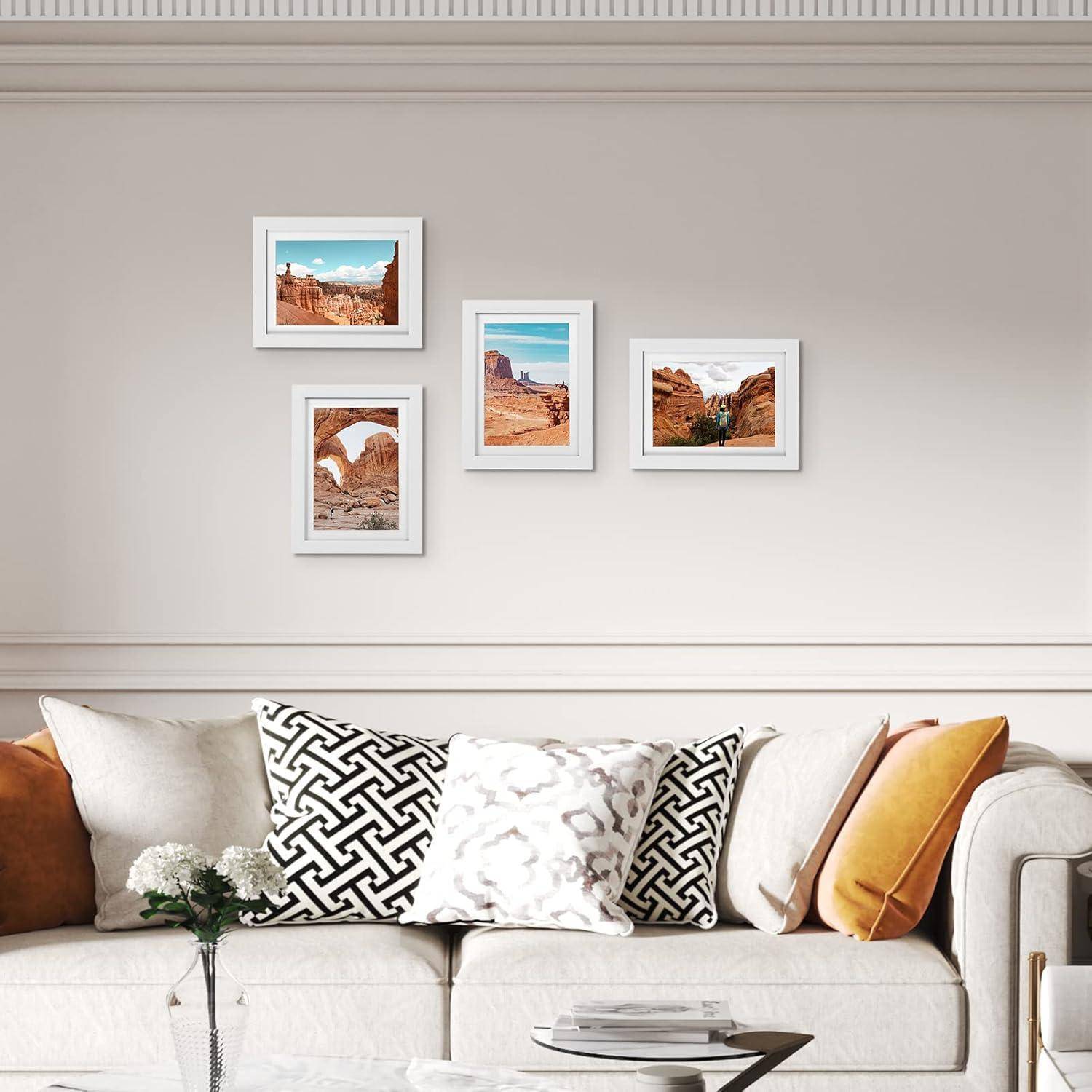 Ein weißes Sofa mit gemusterten und einfarbigen Kissen unter vier gerahmten Wüstenlandschaftsfotos an einer beigefarbenen Wand.