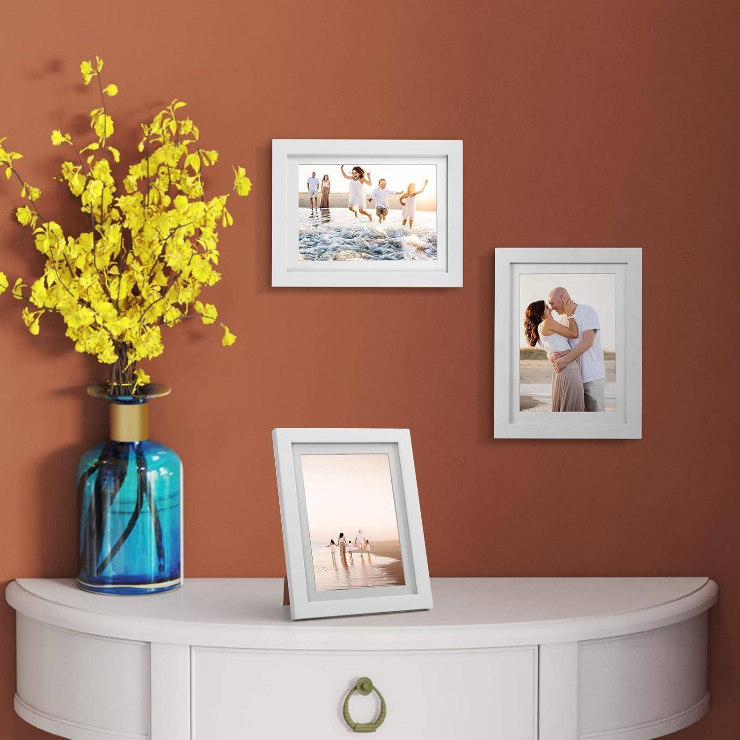 Weißer Konsolentisch an einer rostfarbenen Wand mit einer blauen Vase mit gelben Blumen und drei gerahmten Familienfotos.