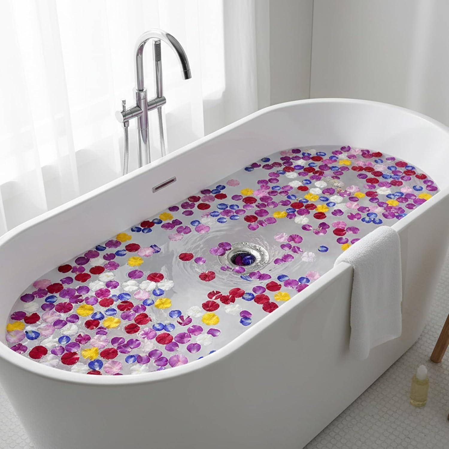 Freistehende weiße Badewanne gefüllt mit Wasser und bunten Blütenblättern in einem hellen Badezimmer, mit einem Chromhahn und einem Handtuch in der Nähe.