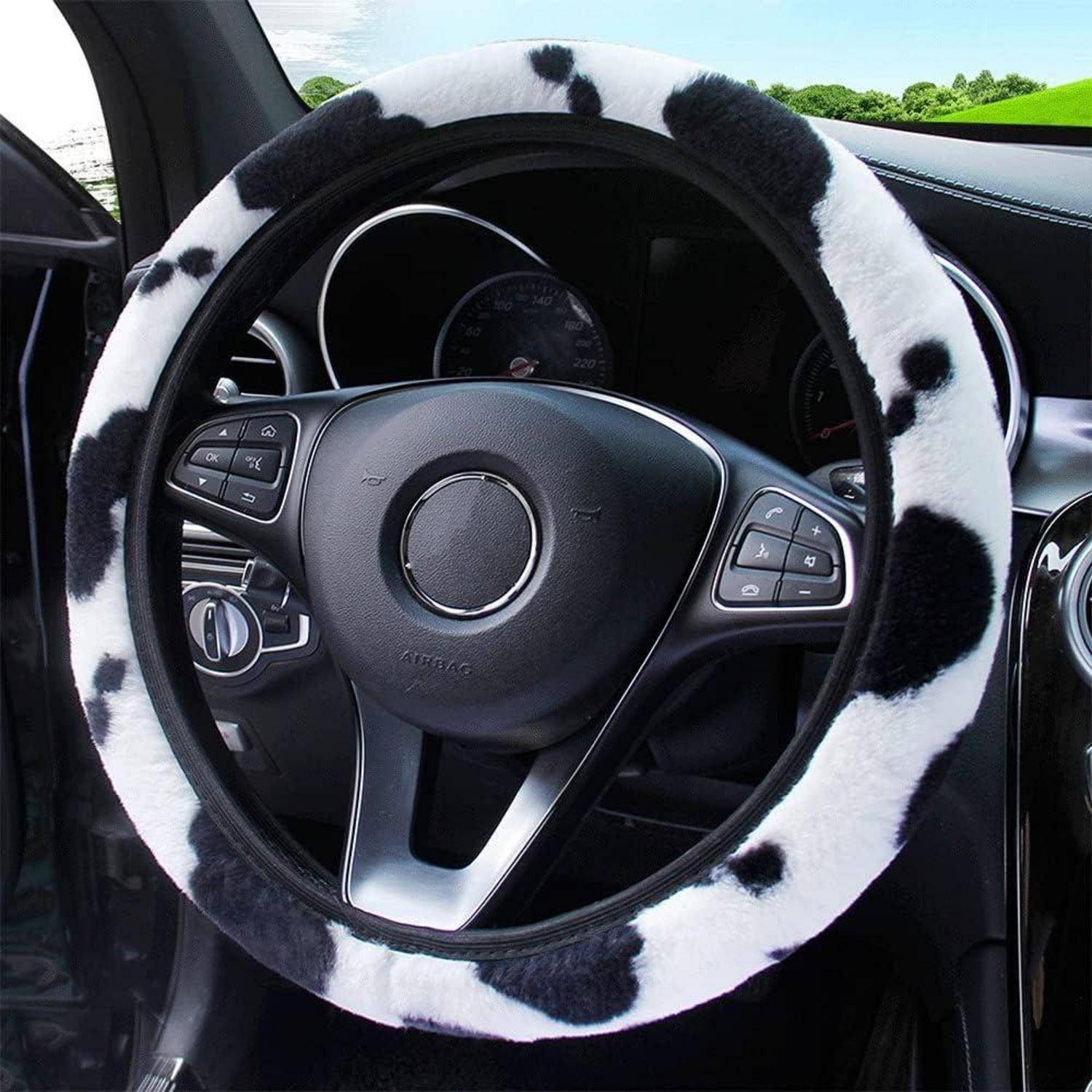 Lenkrad eines Autos mit schwarzweißer Flockenbezug in einem Autoinnenraum bedeckt.