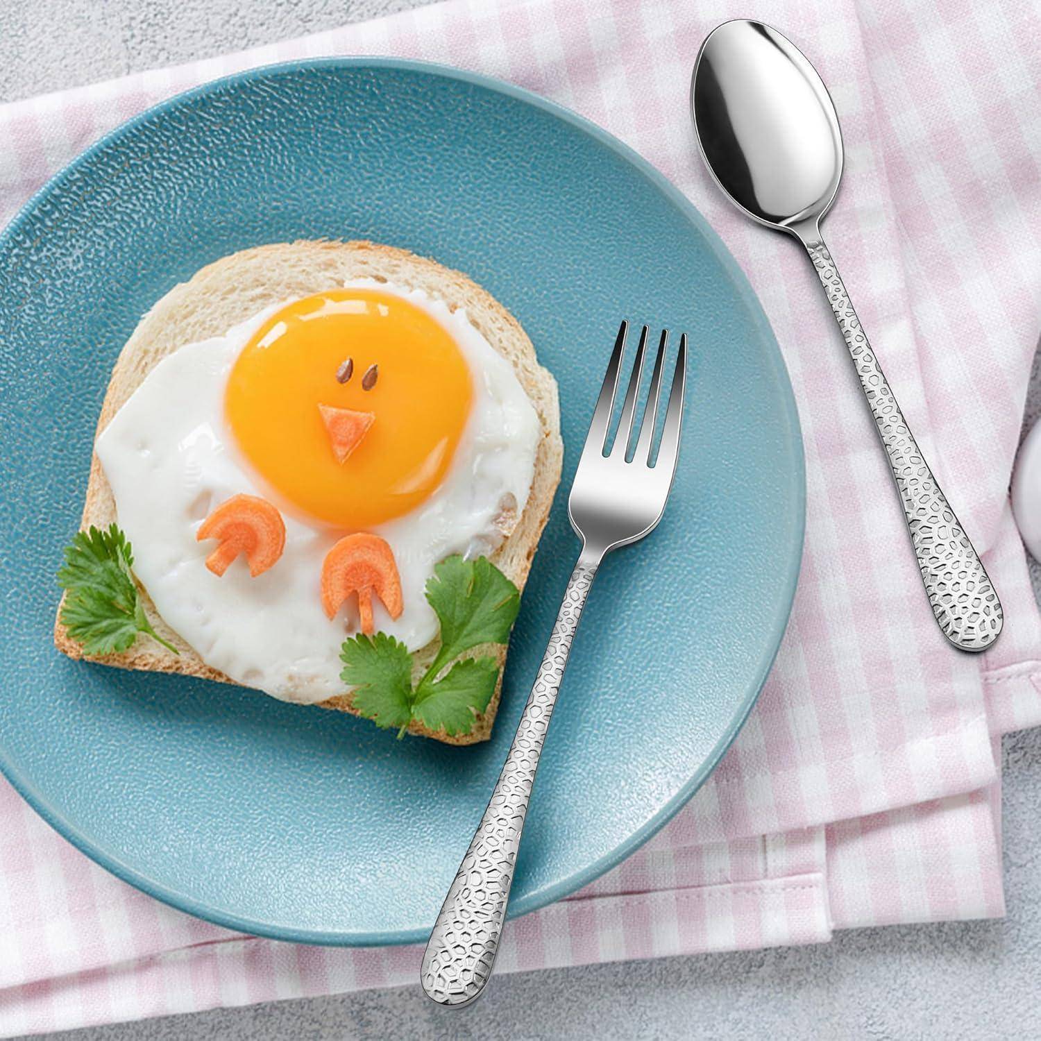 Spiegelei auf Toast, wie ein Vogelgesicht auf einem blauen Teller arrangiert, mit Gabel und Löffel auf einem rosa karierten Tuch.