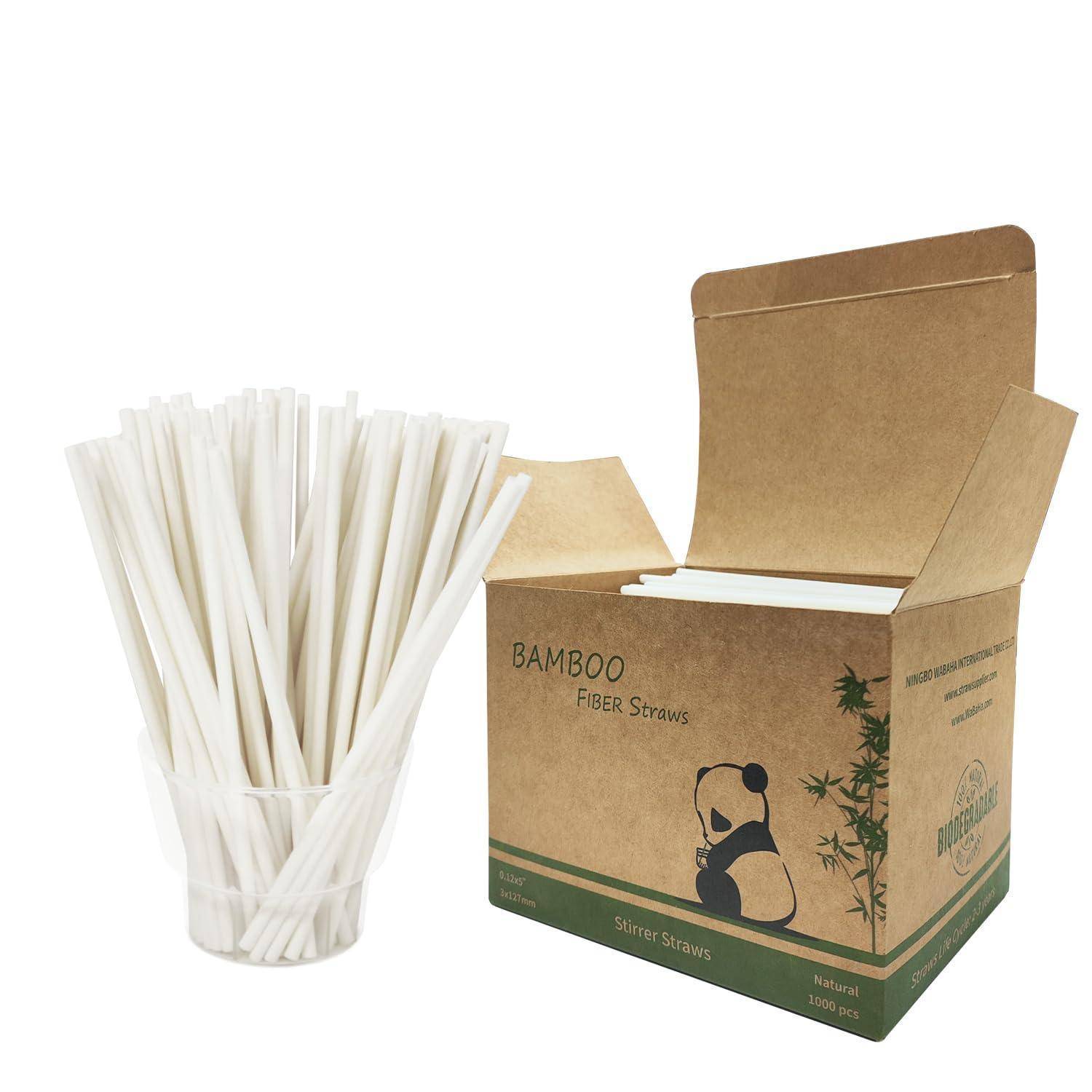 Ein Bündel weißer Strohhalme in einem klaren Becher neben einer offenen Pappschachtel mit der Aufschrift „Bamboo Fiber Straws