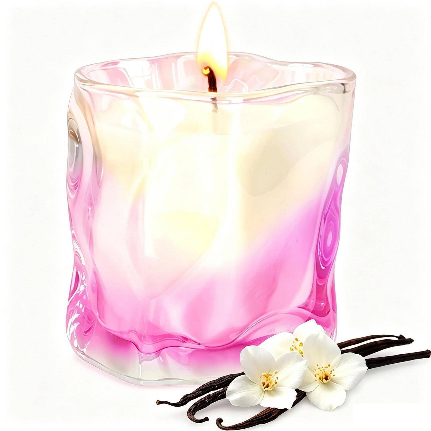 Brennende rosa-weiße Kerze in einem klaren Glashalter mit Vanille-Orchideenblüten und Schoten daneben auf weißem Hintergrund.