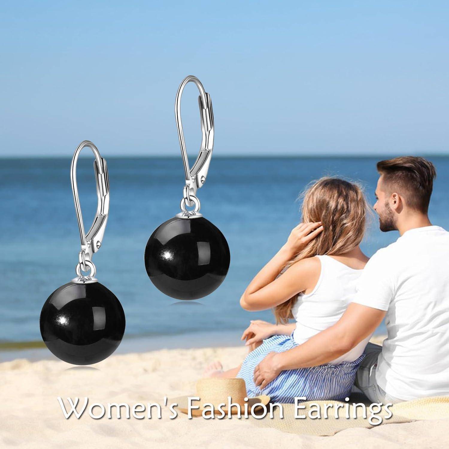 Schwarze Kugel-Hängerohrringe mit silbernen Haken auf einer Strandszene neben einem Paar ausgestellt, mit dem Text „Damenmode-Ohrringe