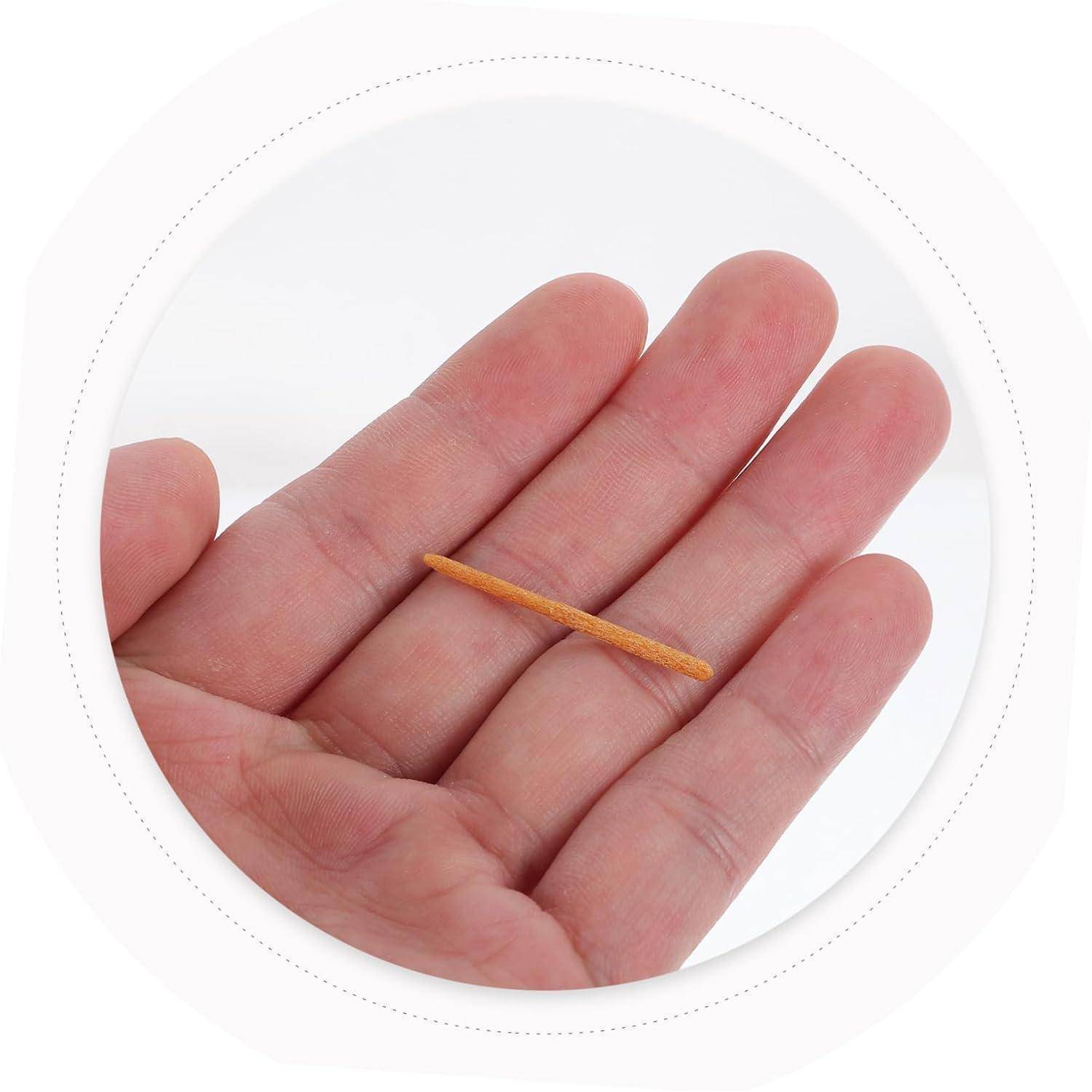 Nahaufnahme einer Hand, die einen winzigen hölzernen Zahnstocher oder ein Streichholz auf der Handfläche gegen einen weißen Hintergrund hält.