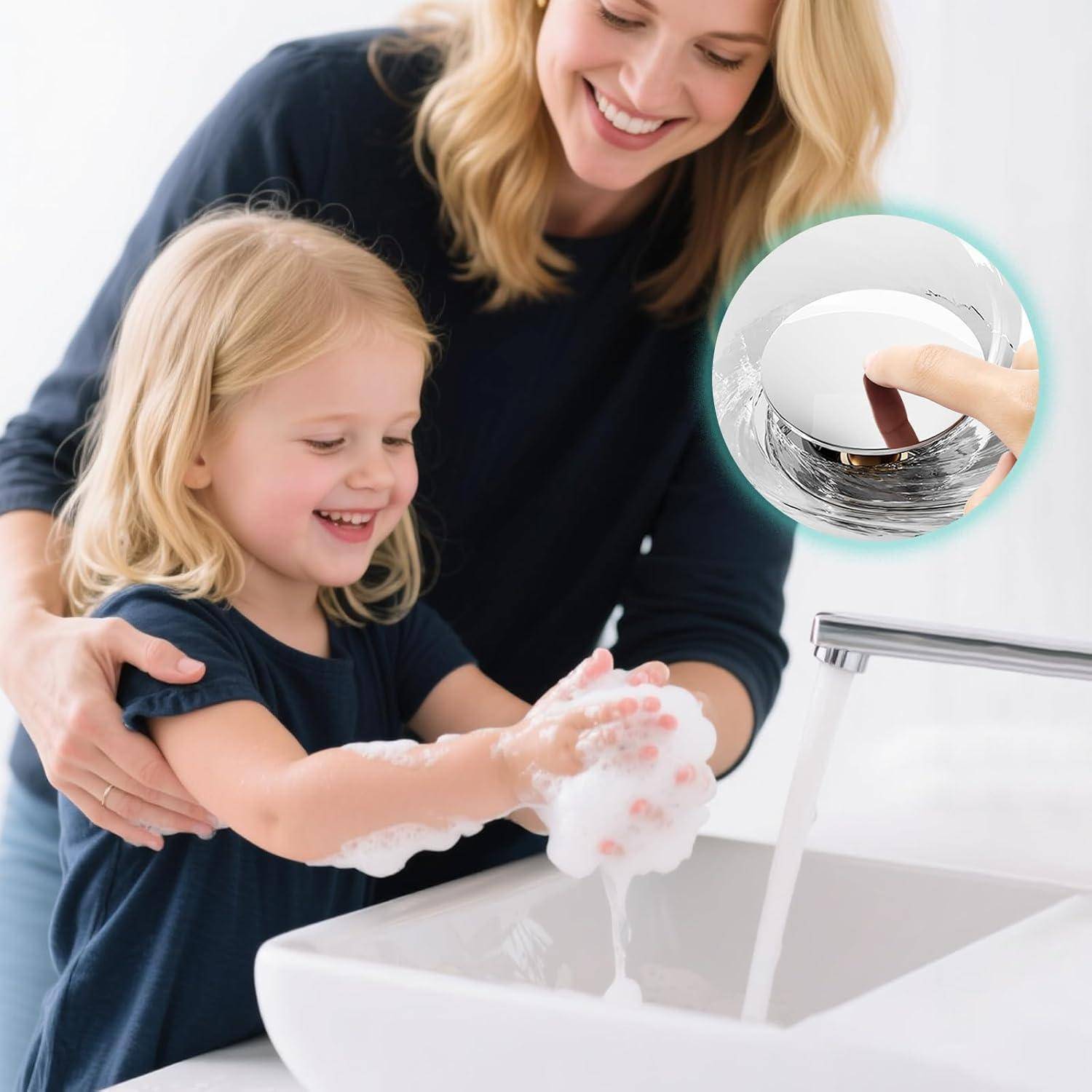 Mutter hilft jungem Mädchen, seifige Hände an einem Waschbecken im Badezimmer zu waschen, mit einer Vergrößerung, die einen Finger zeigt, der den Ablaufstöpsel des Wasserhahns drückt.